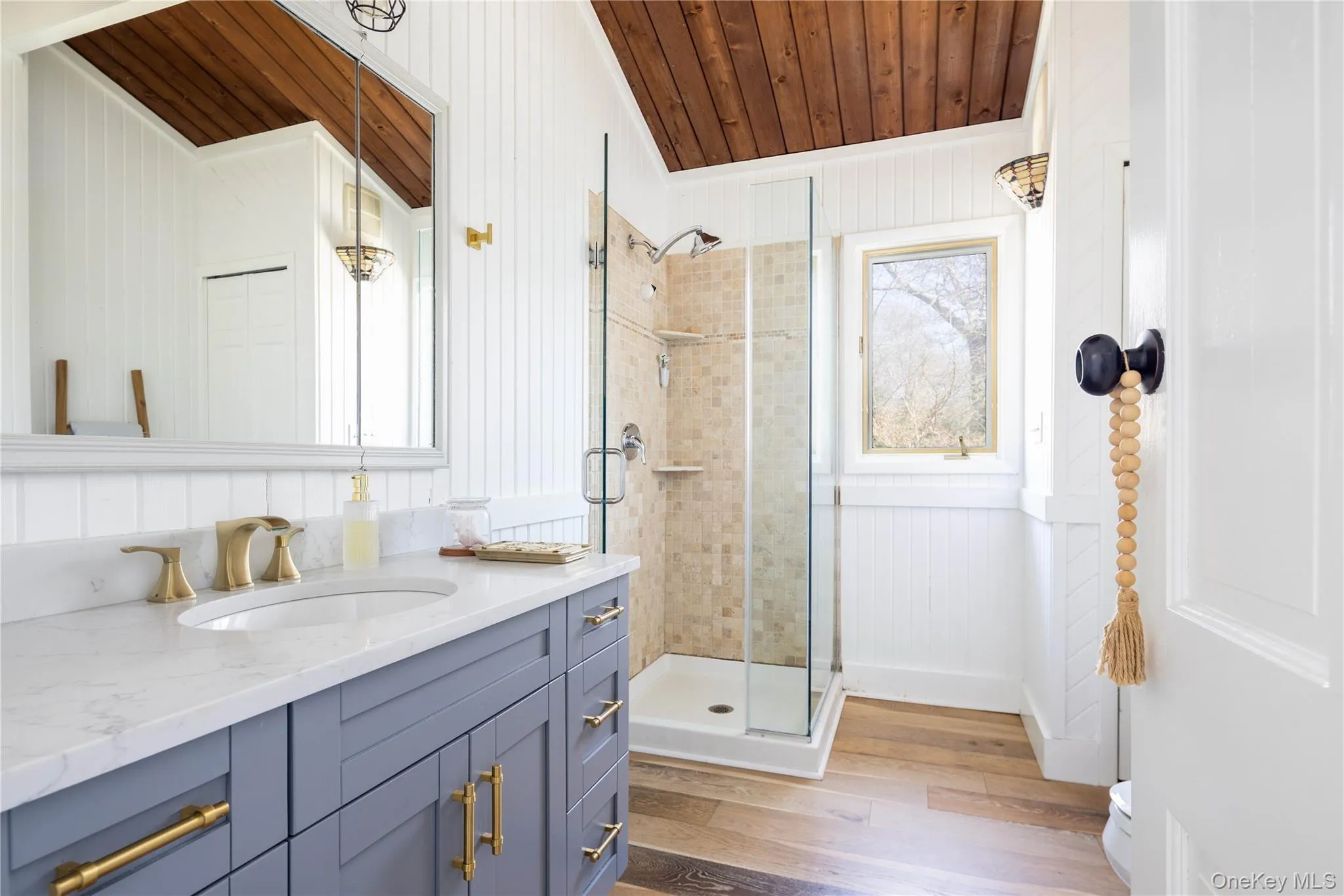 Full bathroom featuring vanity, light wood-type flooring, a shower stall, wood ceiling, and wood walls Full bathroom featuring vanity, light wood-type flooring, a shower stall, wood ceiling, and wood walls