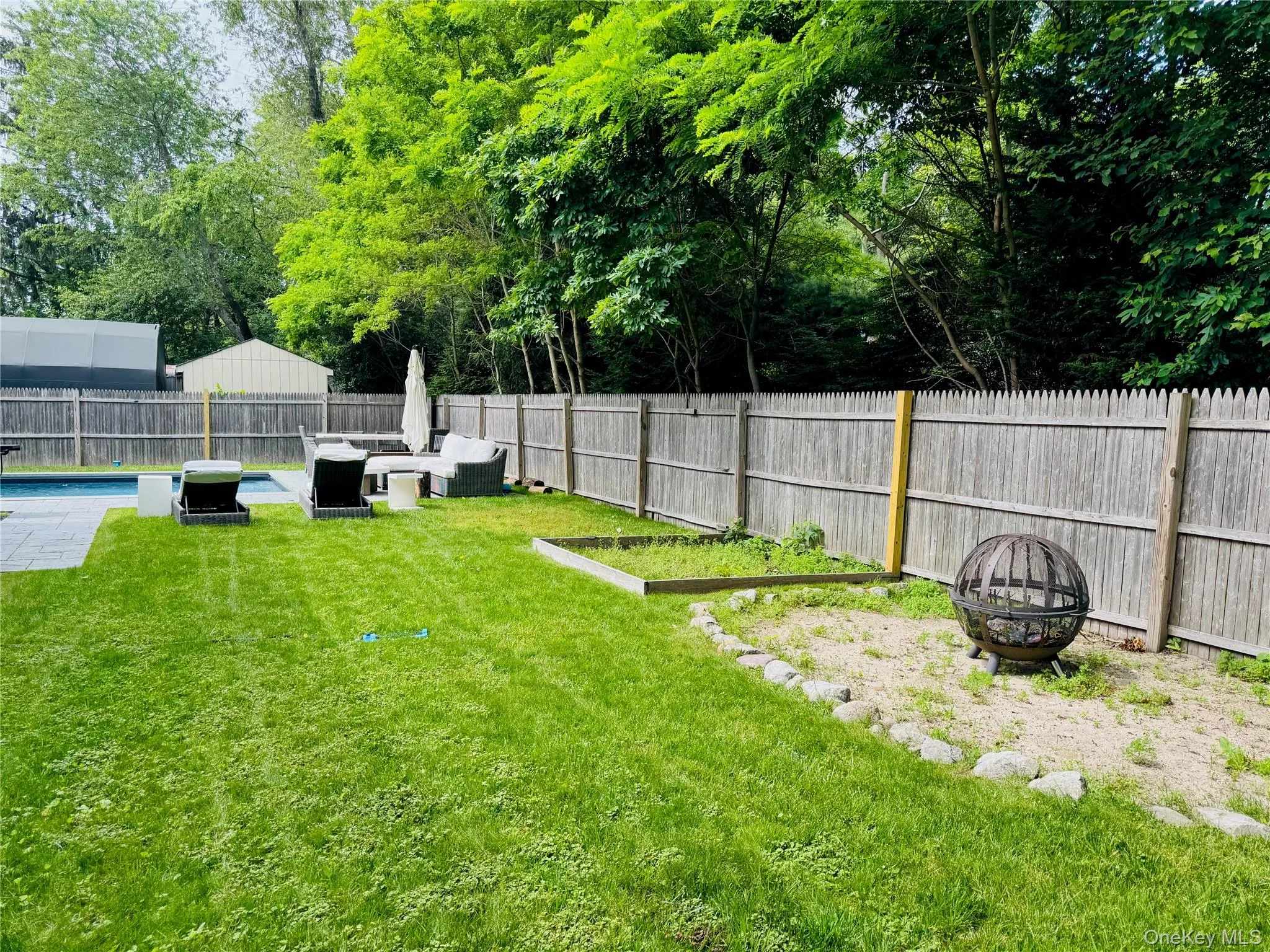 Fenced backyard featuring an outdoor living space with a fire pit and a patio Fenced backyard featuring an outdoor living space with a fire pit and a patio