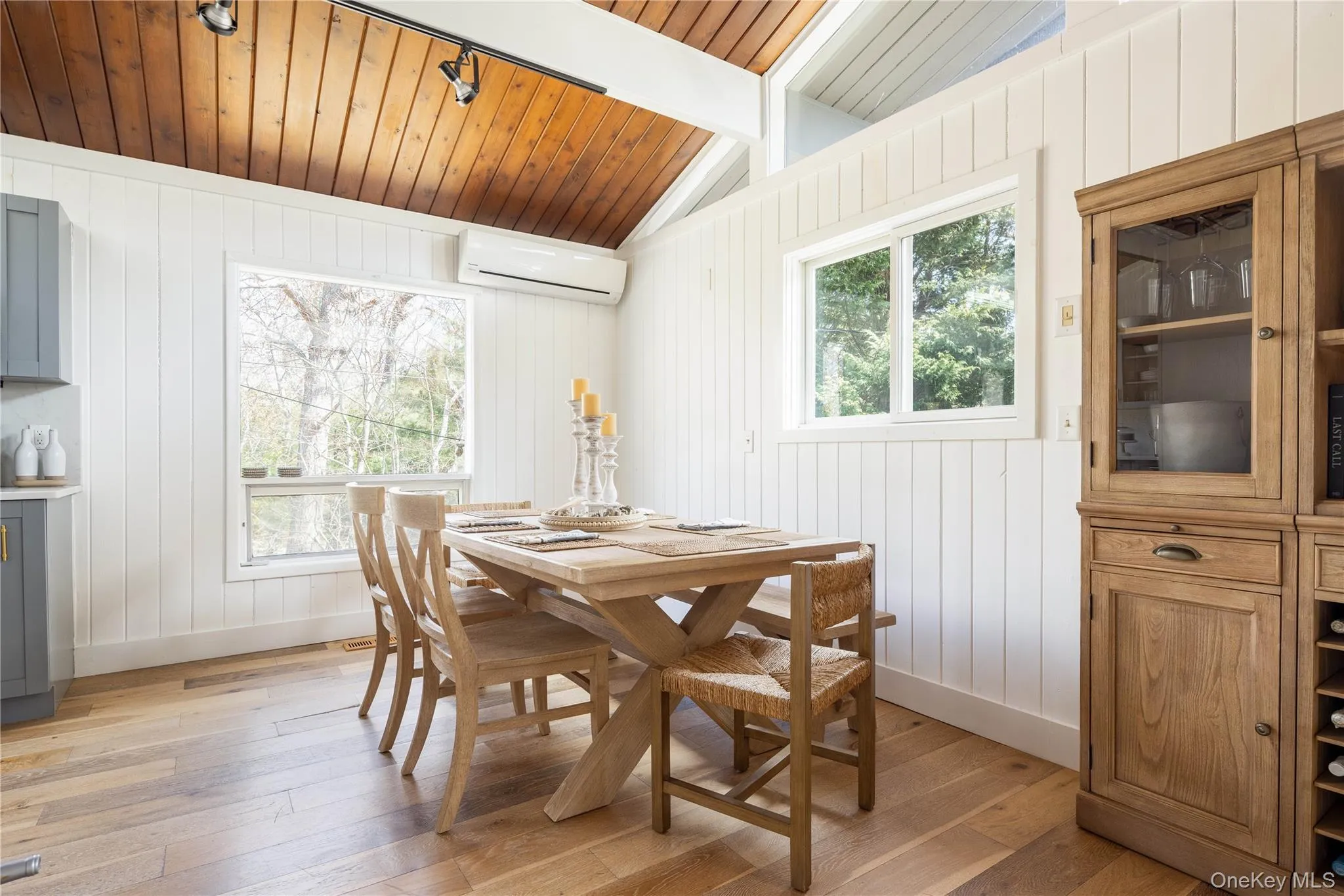 Dining room featuring wooden ceiling, light wood-style floors, plenty of natural light, wood walls, and a wall mounted AC Dining room featuring wooden ceiling, light wood-style floors, plenty of natural light, wood walls, and a wall mounted AC