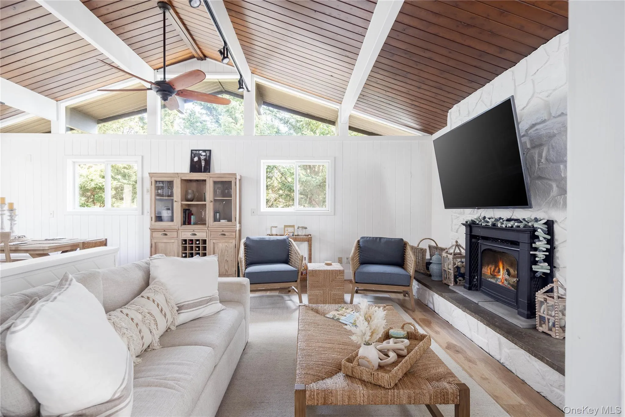 Living area with a large fireplace, wood finished floors, plenty of natural light, lofted ceiling, and wood ceiling Living area with a large fireplace, wood finished floors, plenty of natural light, lofted ceiling, and wood ceiling