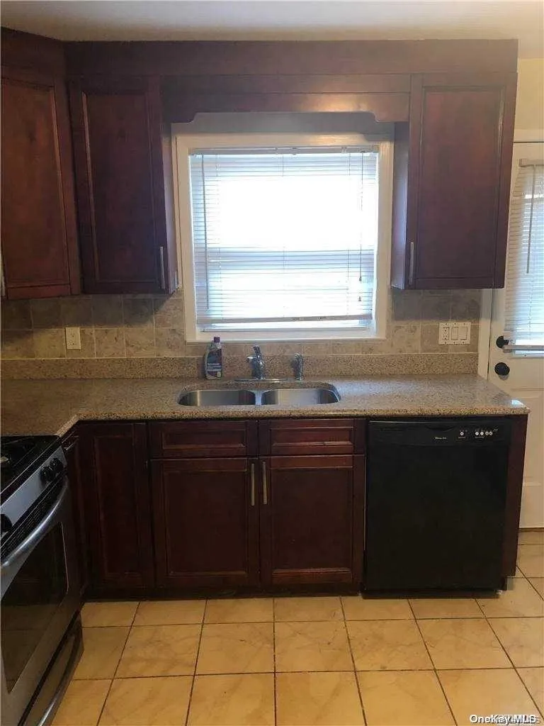 Kitchen featuring range, sink, light tile patterned floors, and black dishwasher Kitchen featuring range, sink, light tile patterned floors, and black dishwasher