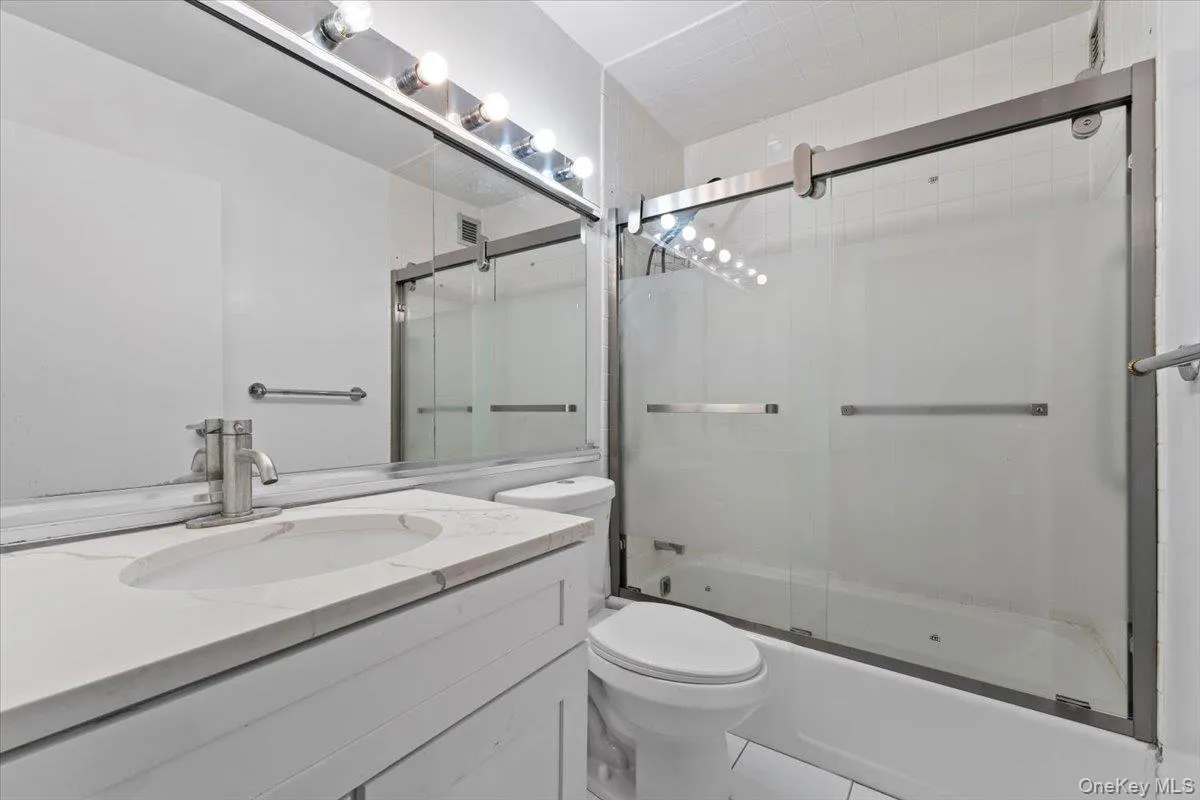 Full bathroom featuring combined bath / shower with glass door and vanity Full bathroom featuring combined bath / shower with glass door and vanity