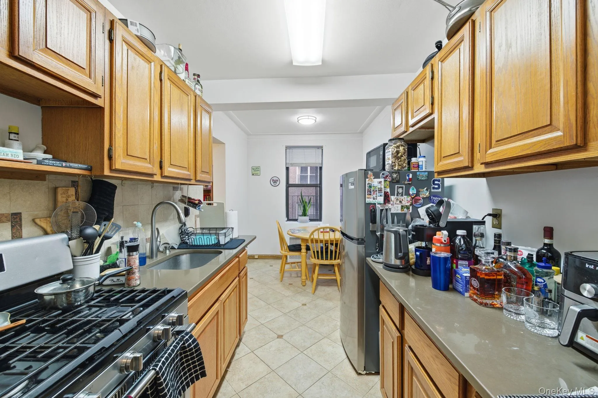 Kitchen featuring appliances with stainless steel finishes, dark stone counters, open shelves, and light tile patterned floors Kitchen featuring appliances with stainless steel finishes, dark stone counters, open shelves, and light tile patterned floors