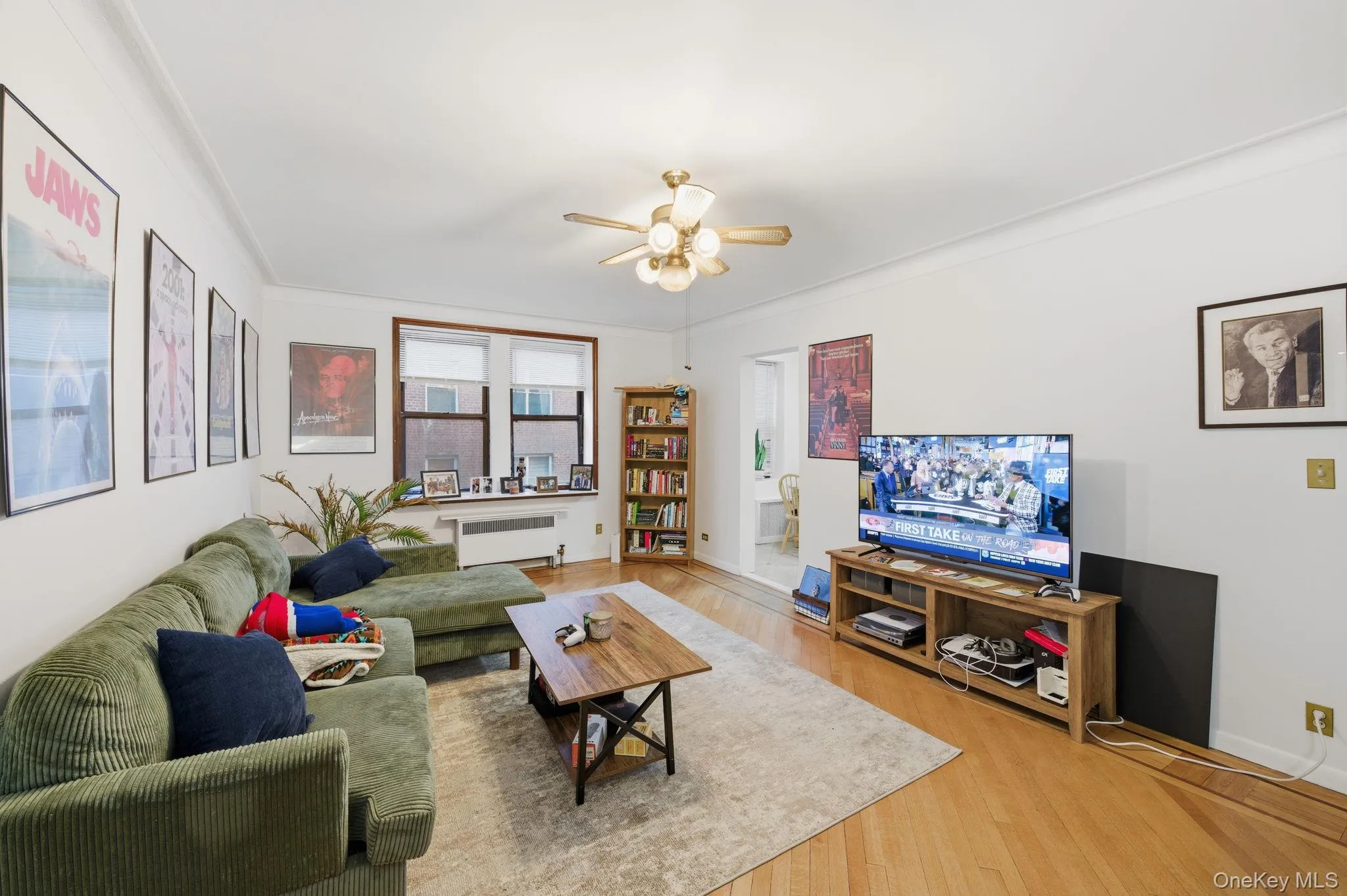 Living room with ornamental molding, wood finished floors, radiator, and a ceiling fan Living room with ornamental molding, wood finished floors, radiator, and a ceiling fan