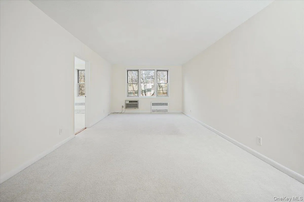 Unfurnished room with radiator heating unit and carpet floors Unfurnished room with radiator heating unit and carpet floors