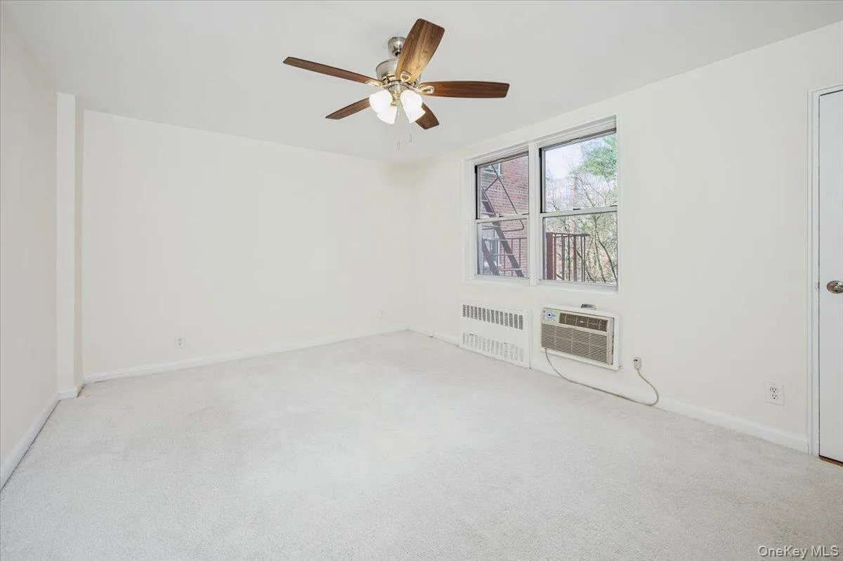 Spare room with radiator, light carpet, and a ceiling fan Spare room with radiator, light carpet, and a ceiling fan
