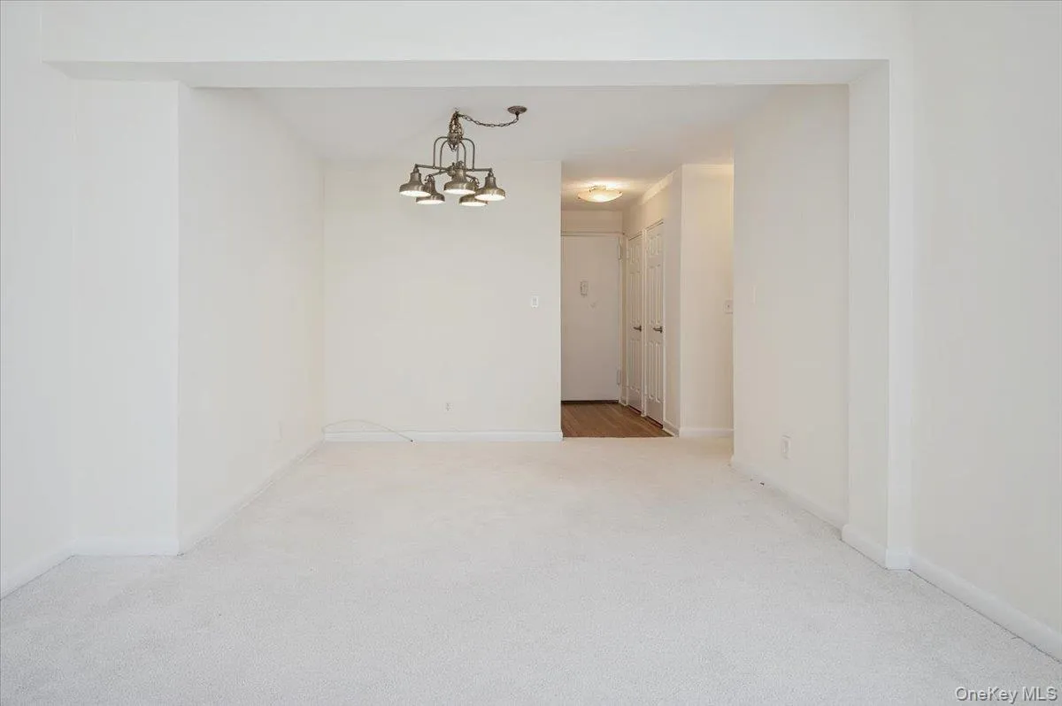 Spare room with a chandelier and light colored carpet Spare room with a chandelier and light colored carpet