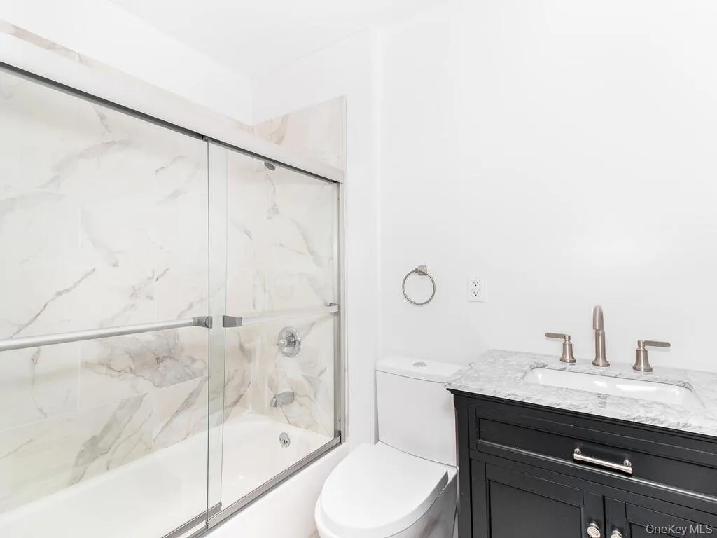 Bathroom featuring toilet, shower / bath combination with glass door, and vanity Bathroom featuring toilet, shower / bath combination with glass door, and vanity
