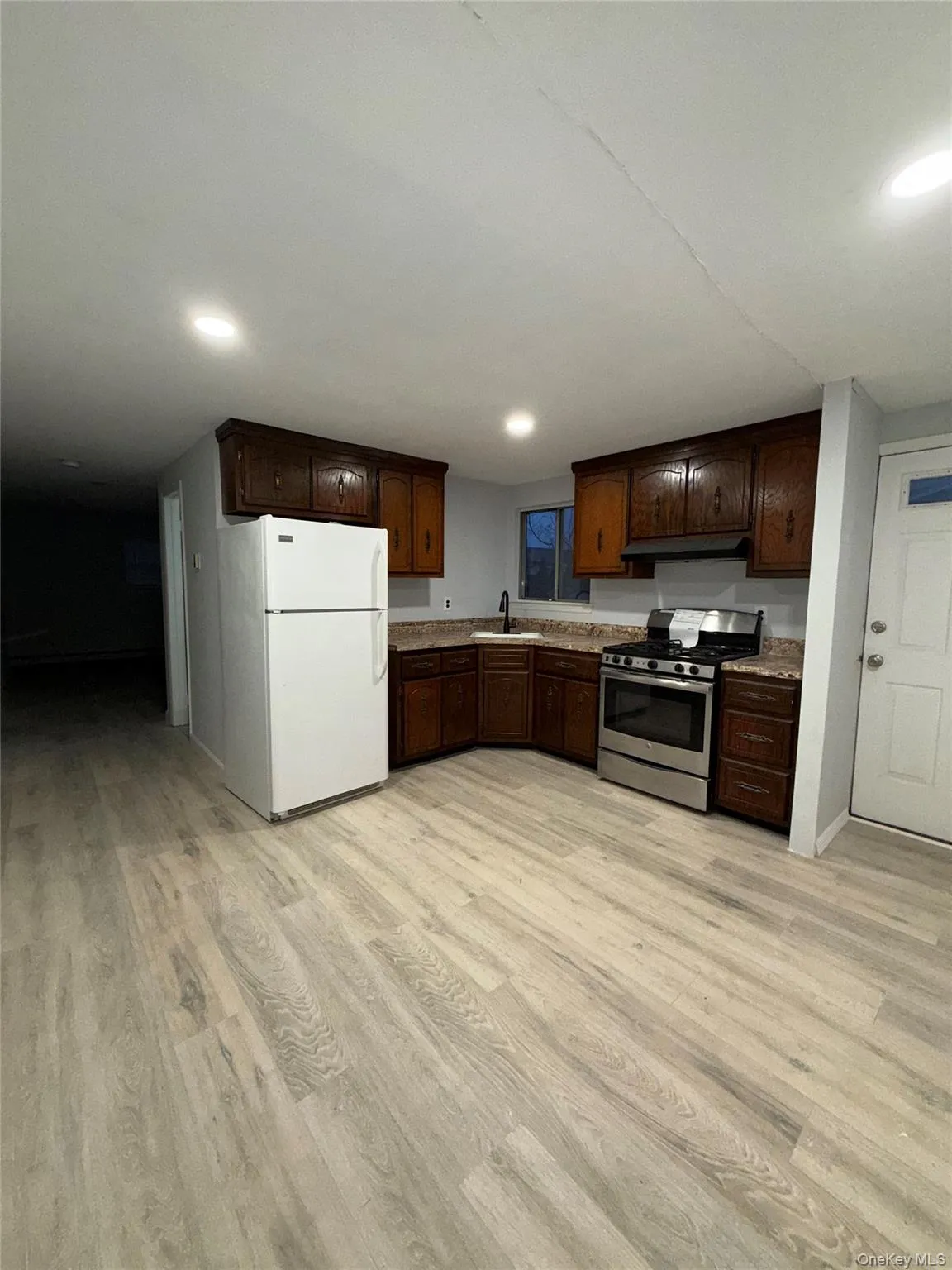 Kitchen featuring freestanding refrigerator, stainless steel gas range, dark brown cabinets, light wood-style floors, and recessed lighting Kitchen featuring freestanding refrigerator, stainless steel gas range, dark brown cabinets, light wood-style floors, and recessed lighting