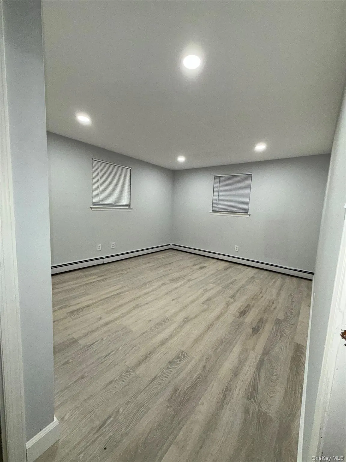 Empty room featuring light wood-style floors, recessed lighting, and a baseboard radiator Empty room featuring light wood-style floors, recessed lighting, and a baseboard radiator