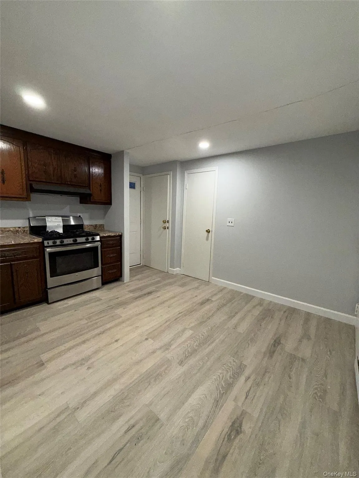 Kitchen featuring stainless steel gas stove, dark brown cabinets, recessed lighting, light wood-type flooring, and light countertops Kitchen featuring stainless steel gas stove, dark brown cabinets, recessed lighting, light wood-type flooring, and light countertops