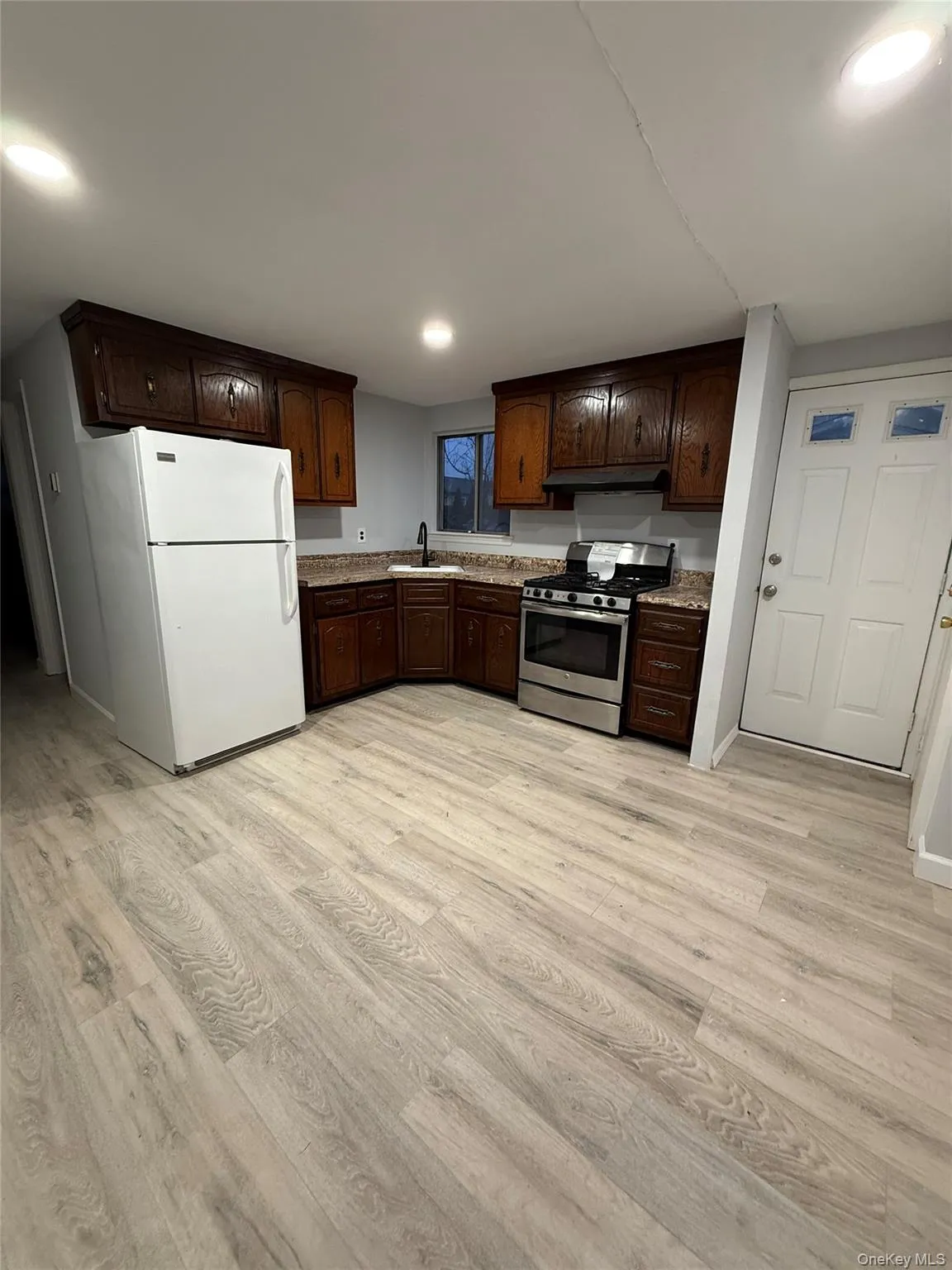 Kitchen featuring freestanding refrigerator, stainless steel range with gas stovetop, dark brown cabinets, light wood-style floors, and recessed lighting Kitchen featuring freestanding refrigerator, stainless steel range with gas stovetop, dark brown cabinets, light wood-style floors, and recessed lighting