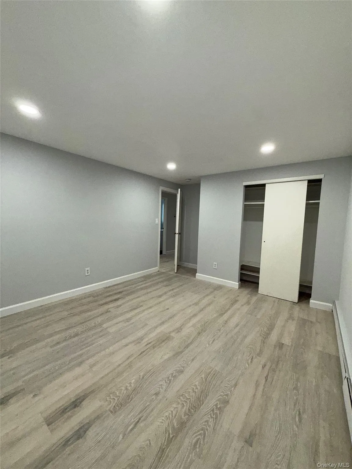 Unfurnished bedroom featuring light wood finished floors, a closet, a baseboard heating unit, and recessed lighting Unfurnished bedroom featuring light wood finished floors, a closet, a baseboard heating unit, and recessed lighting