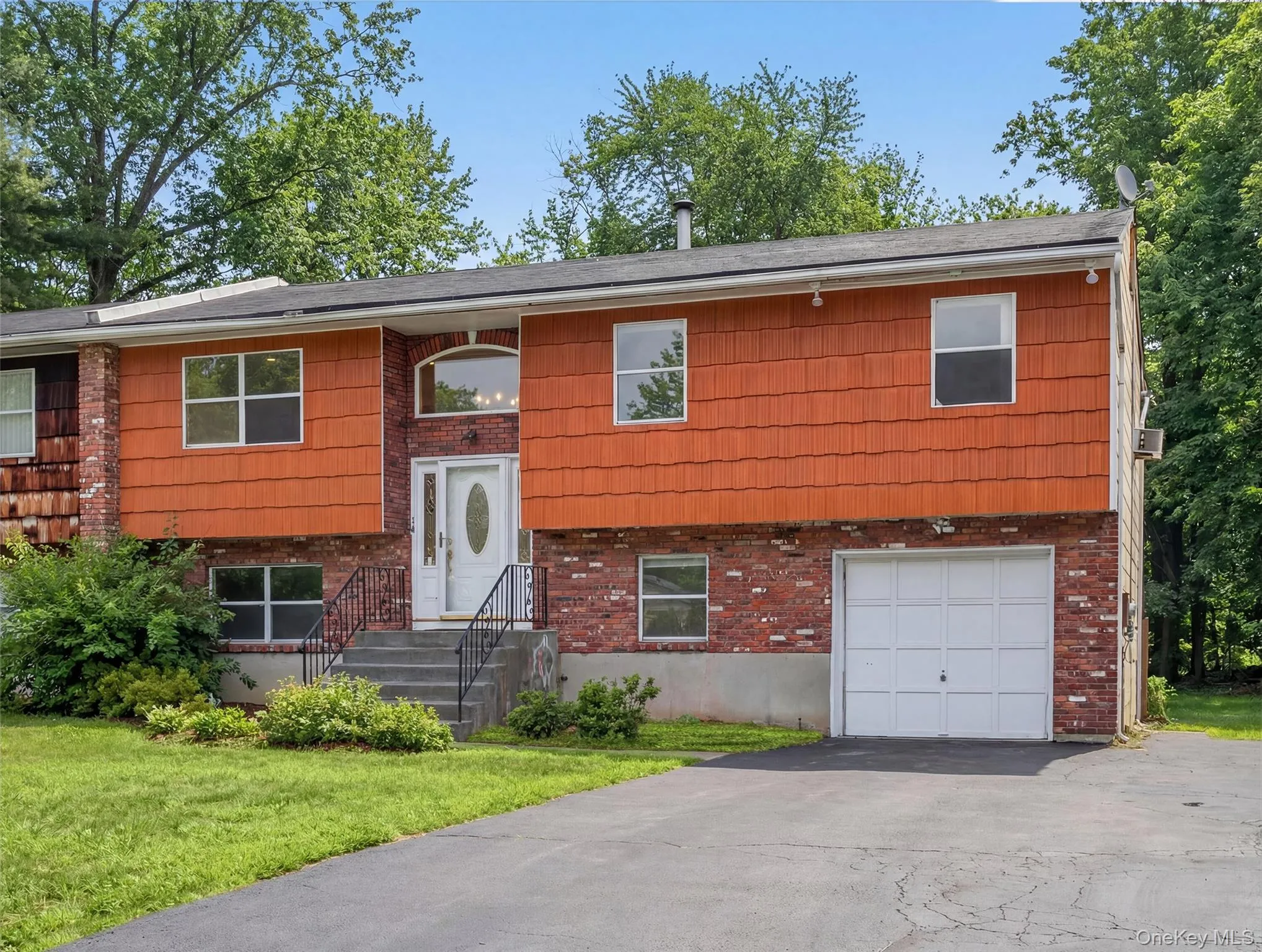 Split foyer home with asphalt driveway, an attached garage, a front yard, and brick siding Split foyer home with asphalt driveway, an attached garage, a front yard, and brick siding