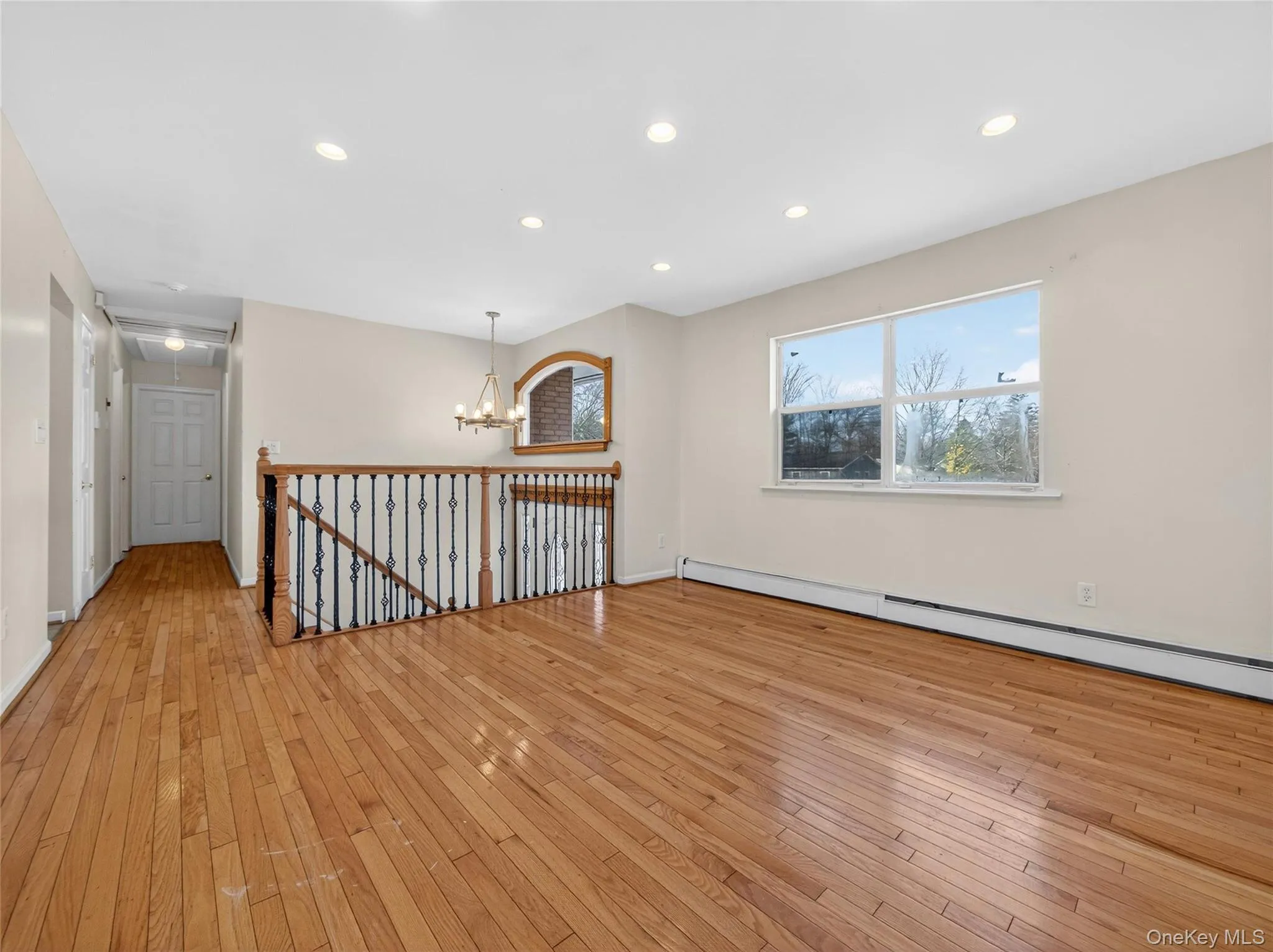 Spare room featuring a baseboard radiator, light wood-type flooring, recessed lighting, and a chandelier Spare room featuring a baseboard radiator, light wood-type flooring, recessed lighting, and a chandelier
