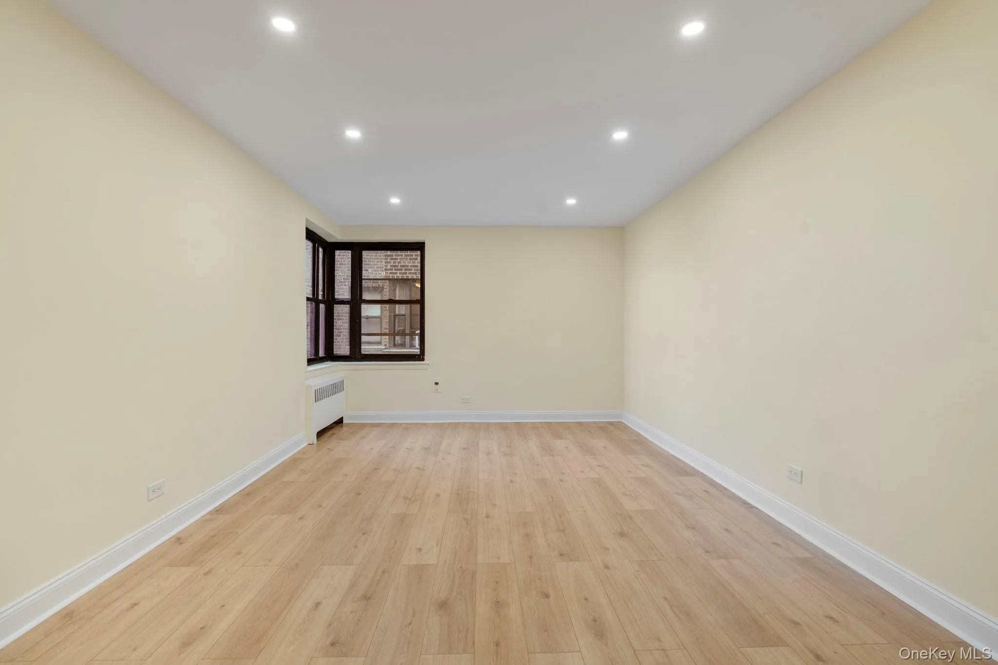 Living room featuring corner window, light wood flooring and recessed lighting Living room featuring corner window, light wood flooring and recessed lighting
