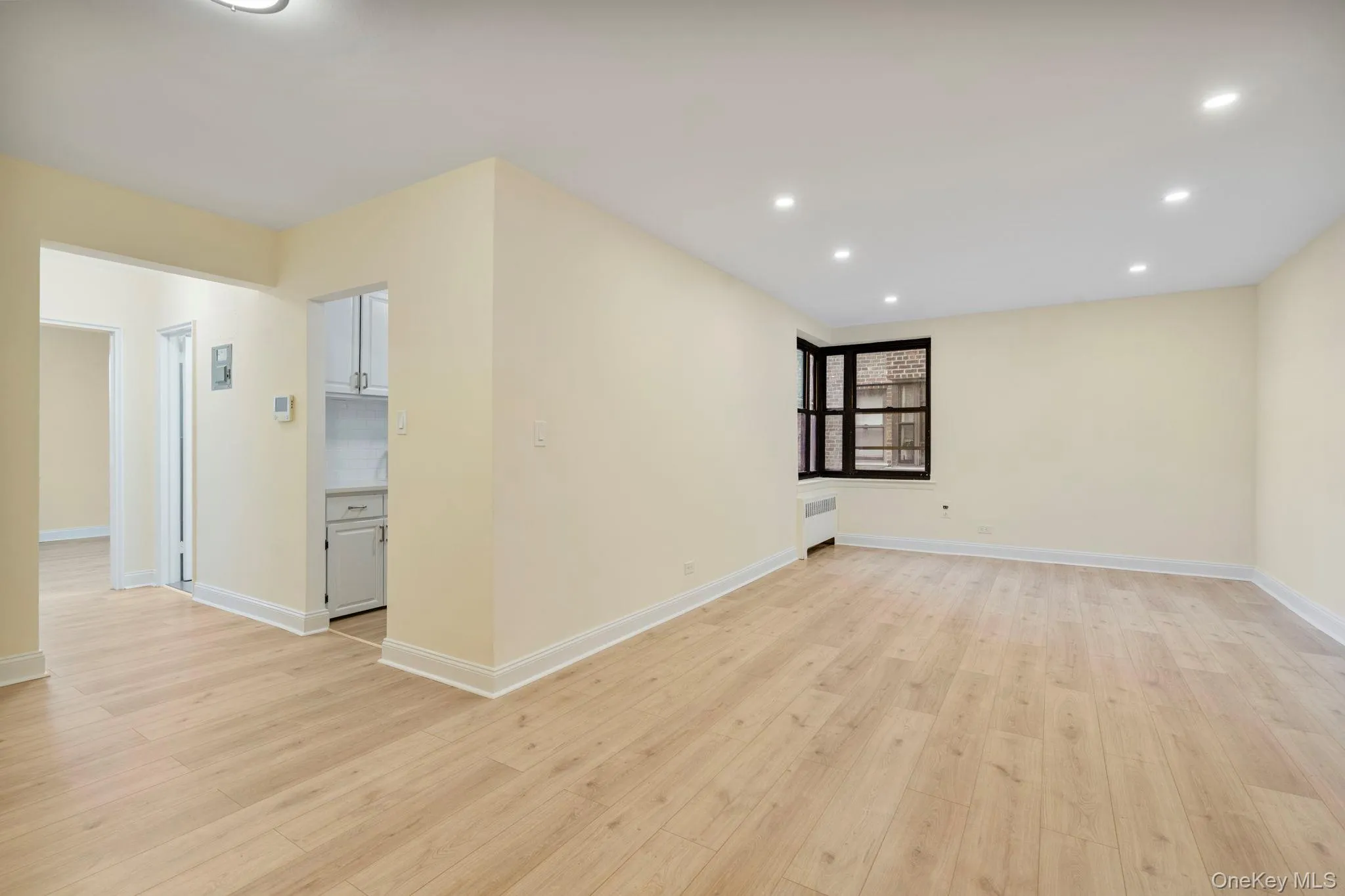 Living room and dining area, featuring light wood finished floors, recessed lighting, and radiator heating unit Living room and dining area, featuring light wood finished floors, recessed lighting, and radiator heating unit