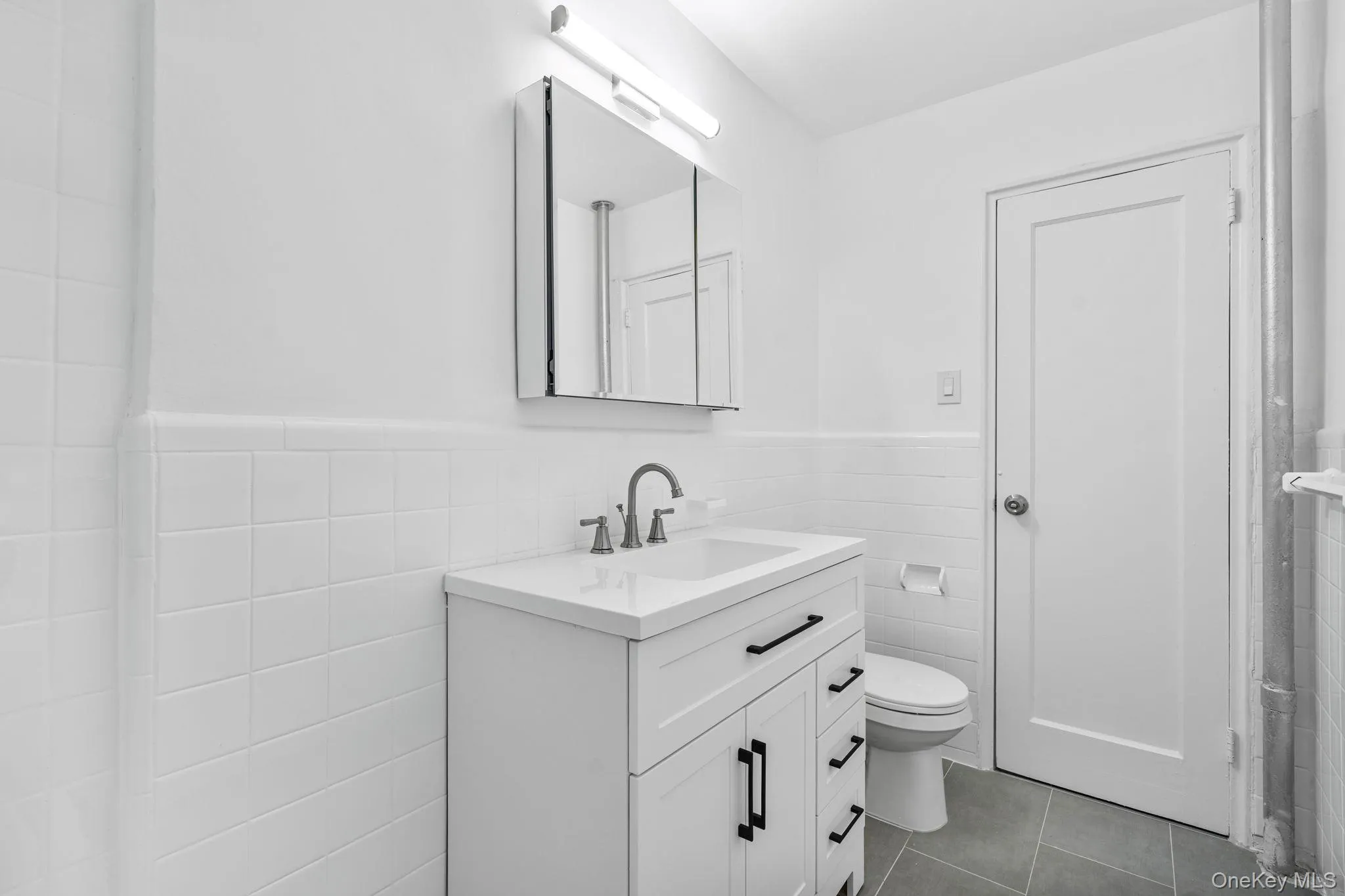 Bathroom featuring vanity, wainscoting, tile walls, and tiled floors Bathroom featuring vanity, wainscoting, tile walls, and tiled floors