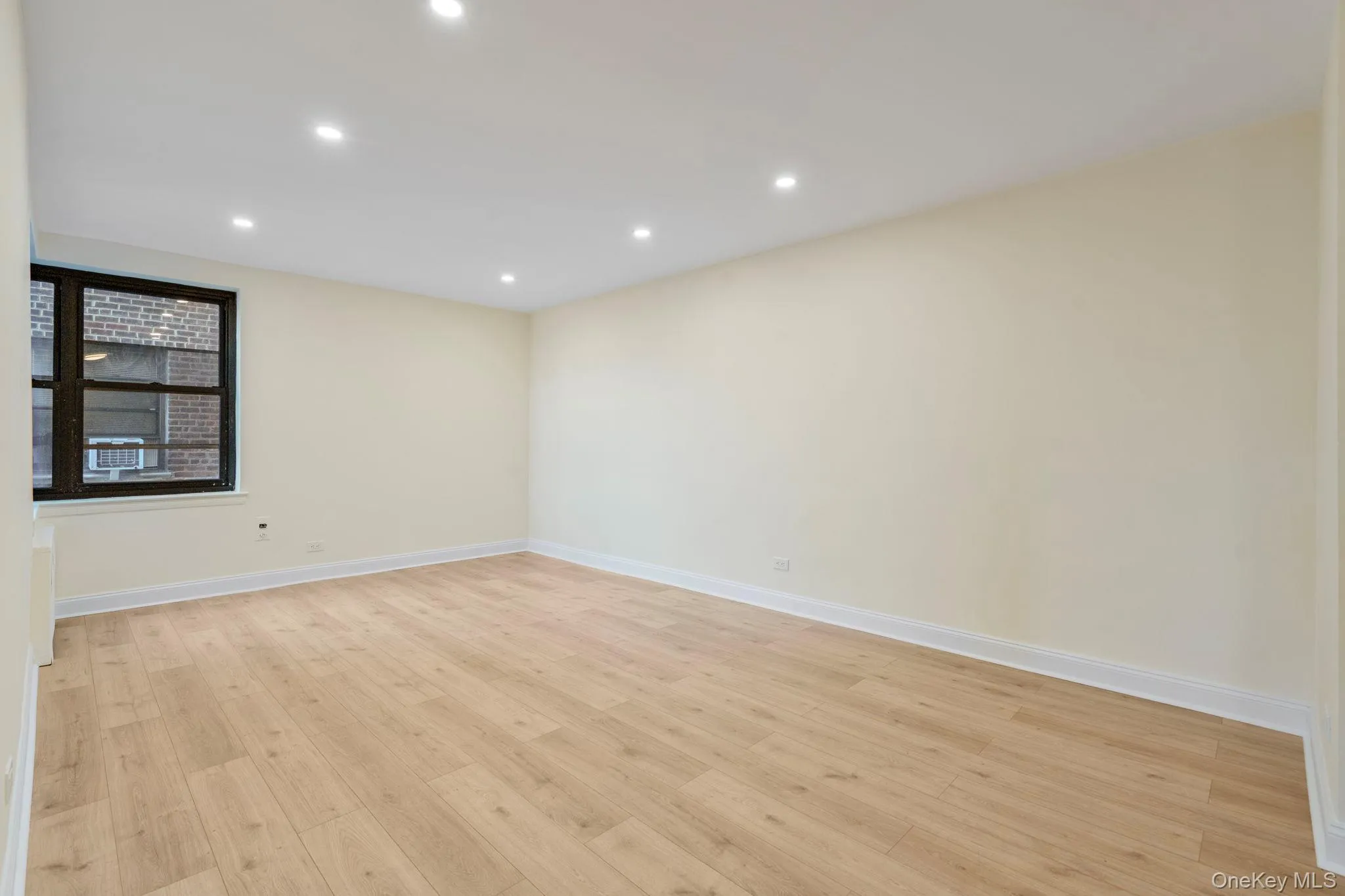 Living room featuring corner window, light wood finished floors and recessed lighting Living room featuring corner window, light wood finished floors and recessed lighting