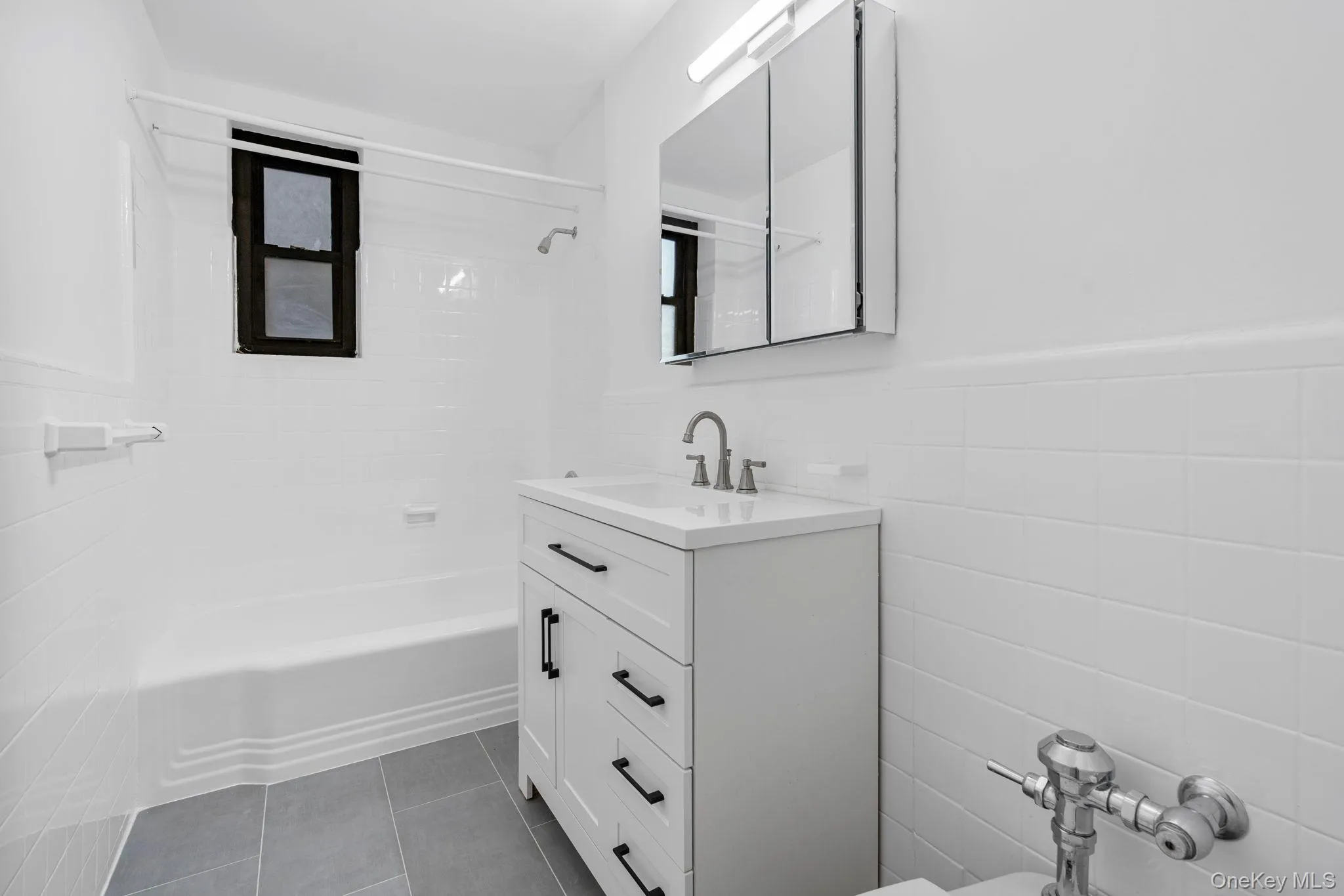 Full bathroom featuring tub / shower combination, vanity, tile walls, a wainscoted wall, and tiled flooring Full bathroom featuring tub / shower combination, vanity, tile walls, a wainscoted wall, and tiled flooring