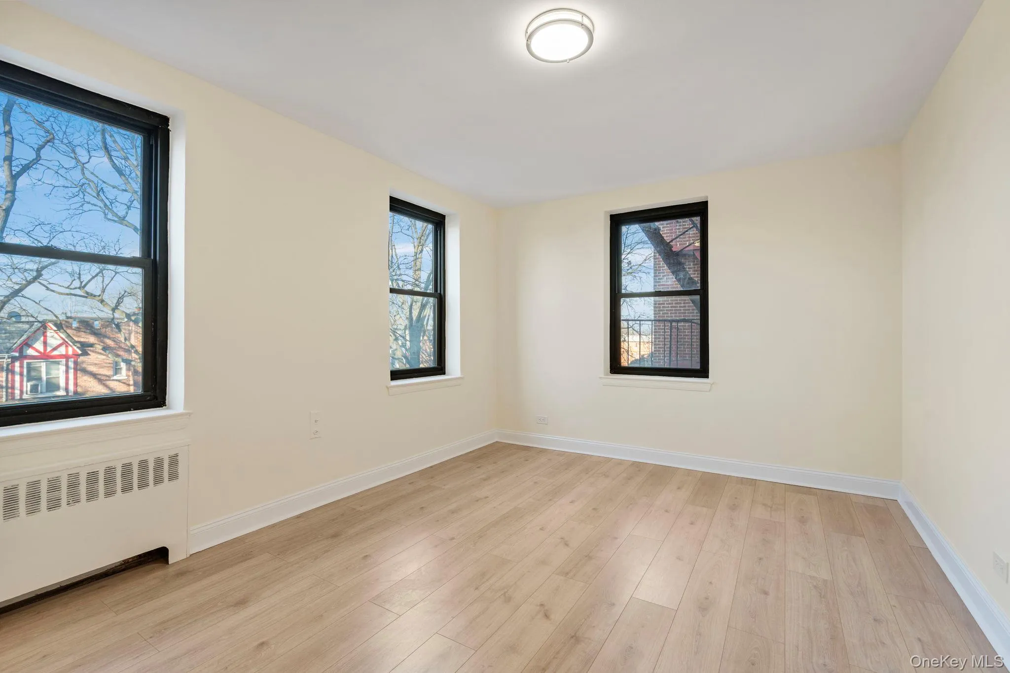 Bedroom with radiator heating unit and light wood-style floors Bedroom with radiator heating unit and light wood-style floors