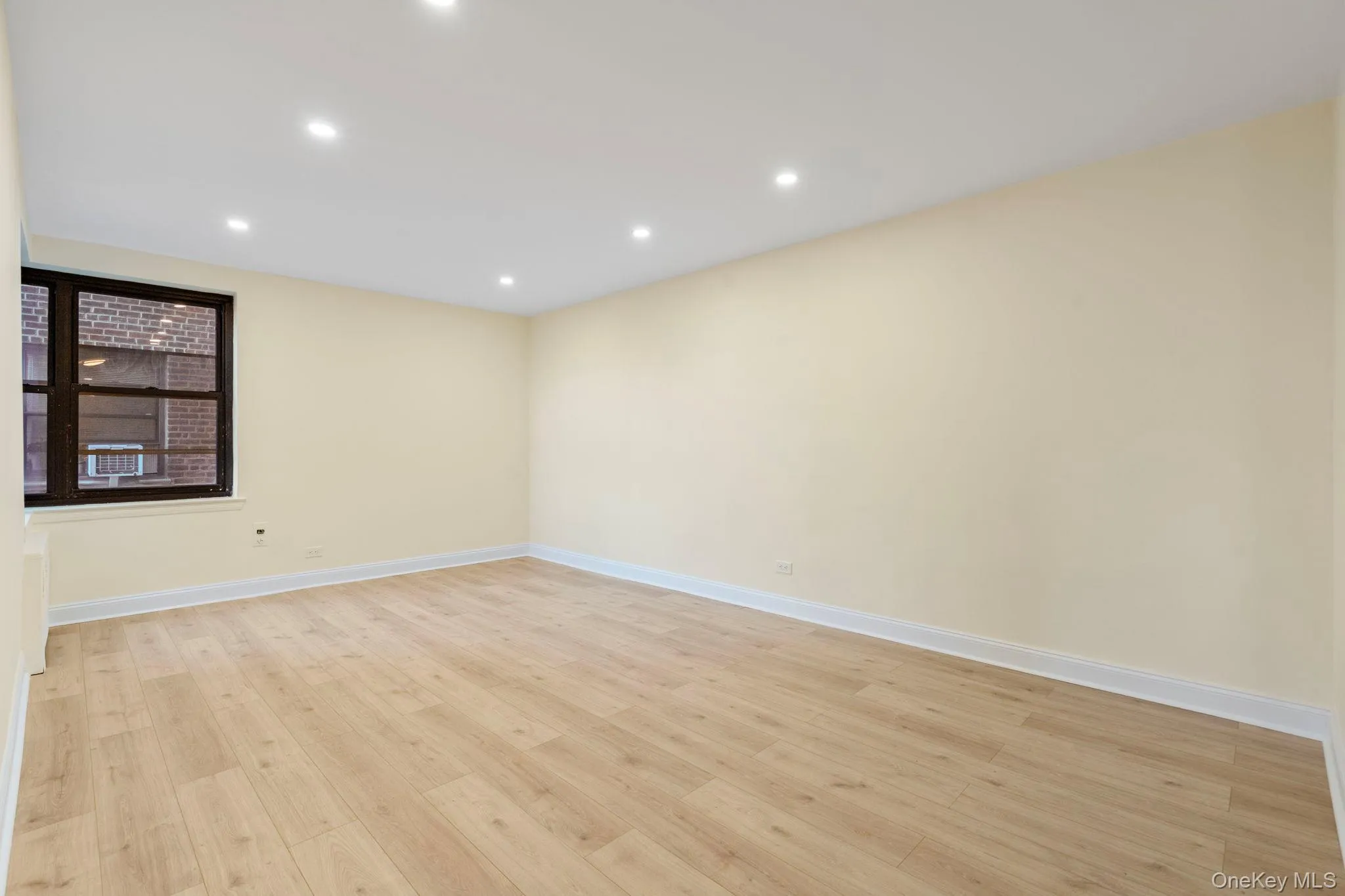 Living room featuring corner window, light wood flooring and recessed lighting Living room featuring corner window, light wood flooring and recessed lighting