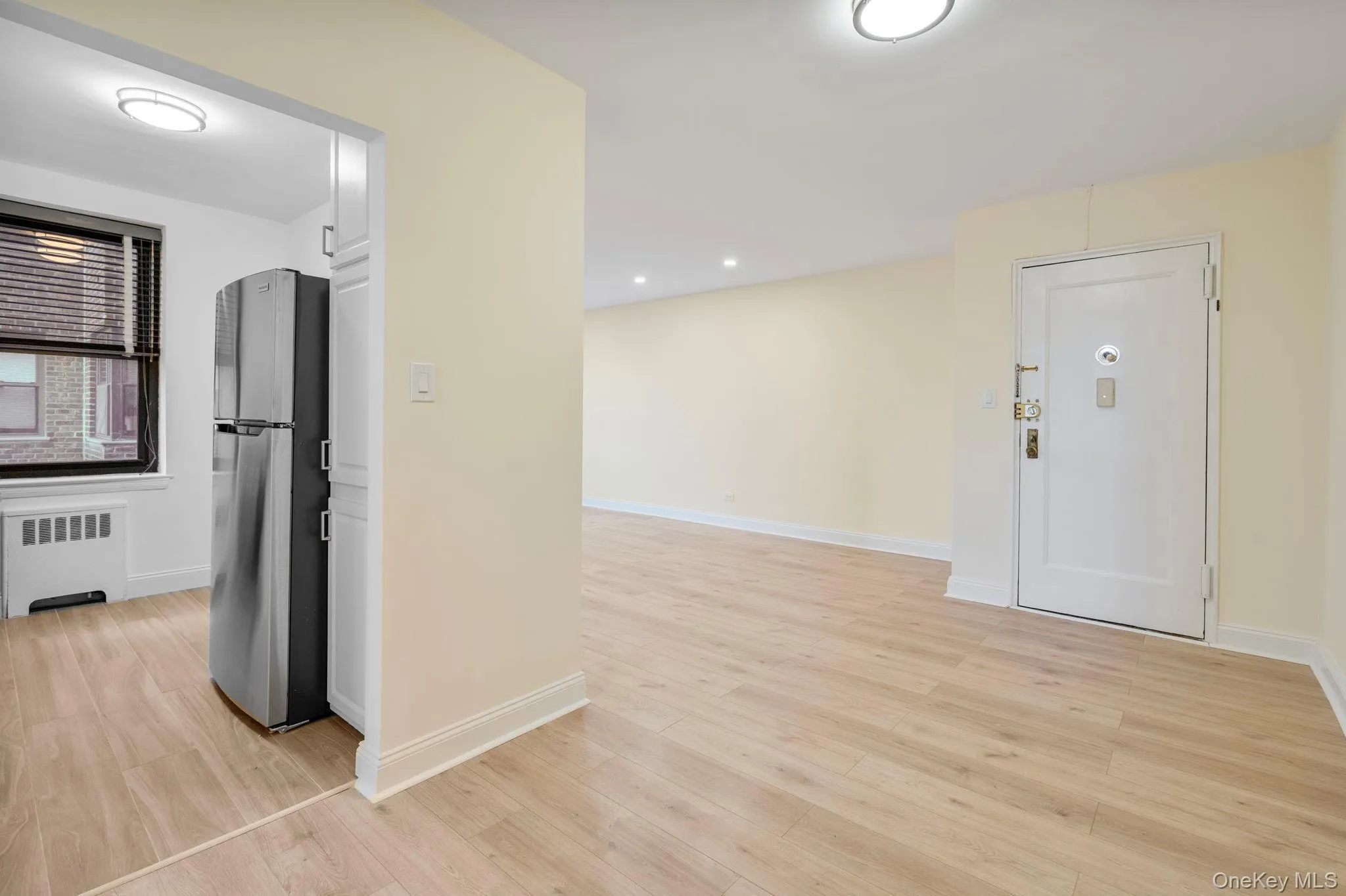 Kitchen featuring freestanding refrigerator, light wood flooring, and radiator Kitchen featuring freestanding refrigerator, light wood flooring, and radiator