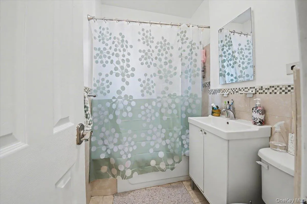 Bathroom with vanity, tile walls, and a shower with curtain Bathroom with vanity, tile walls, and a shower with curtain