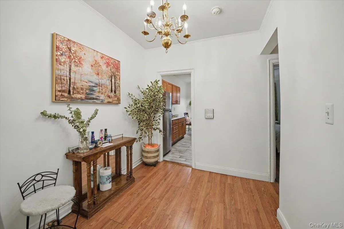 Hallway with a chandelier, light wood-style floors, and crown molding Hallway with a chandelier, light wood-style floors, and crown molding