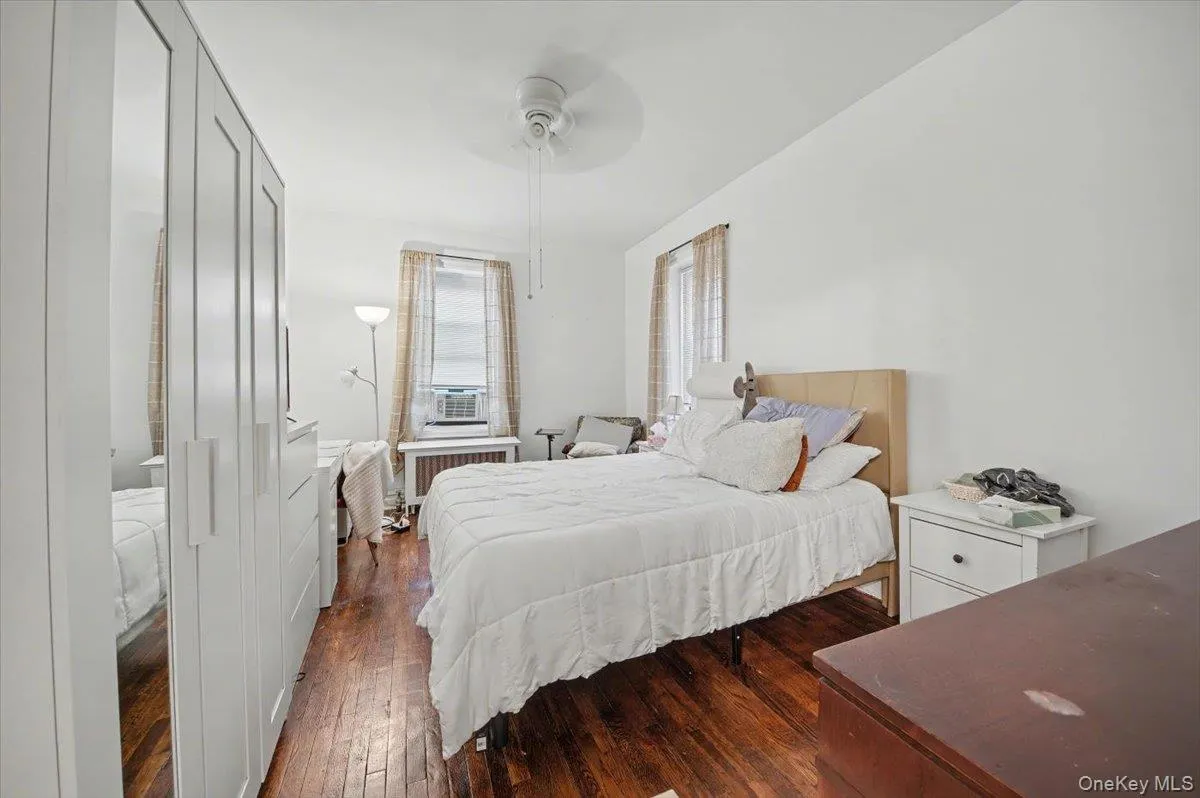 Bedroom featuring dark wood-type flooring, radiator heating unit, ceiling fan, and cooling unit Bedroom featuring dark wood-type flooring, radiator heating unit, ceiling fan, and cooling unit