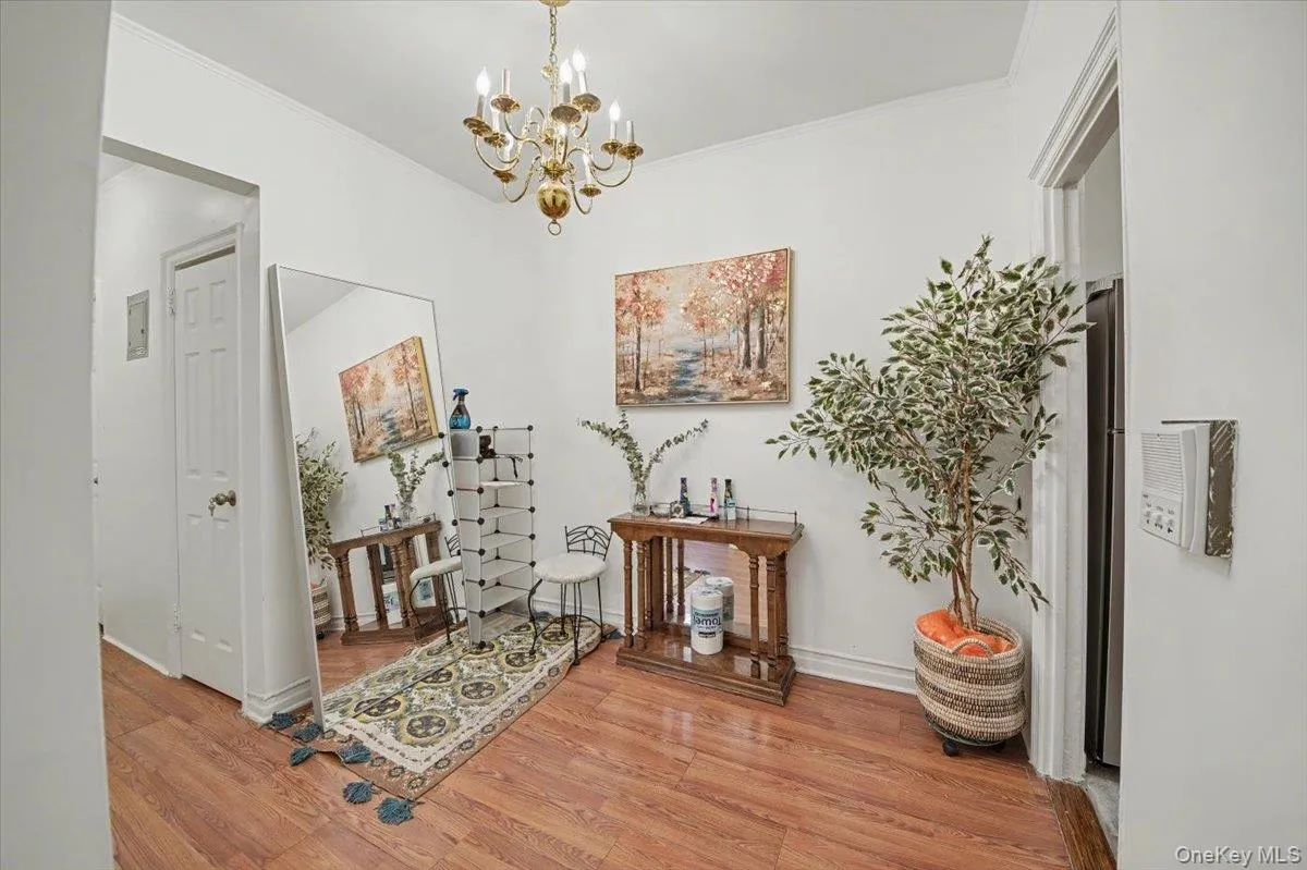 Corridor with a chandelier, light wood-style flooring, and crown molding Corridor with a chandelier, light wood-style flooring, and crown molding