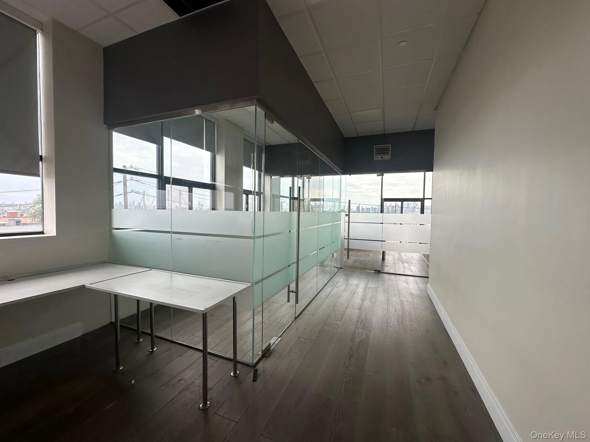 Hall featuring plenty of natural light, a drop ceiling, and dark wood-type flooring Hall featuring plenty of natural light, a drop ceiling, and dark wood-type flooring