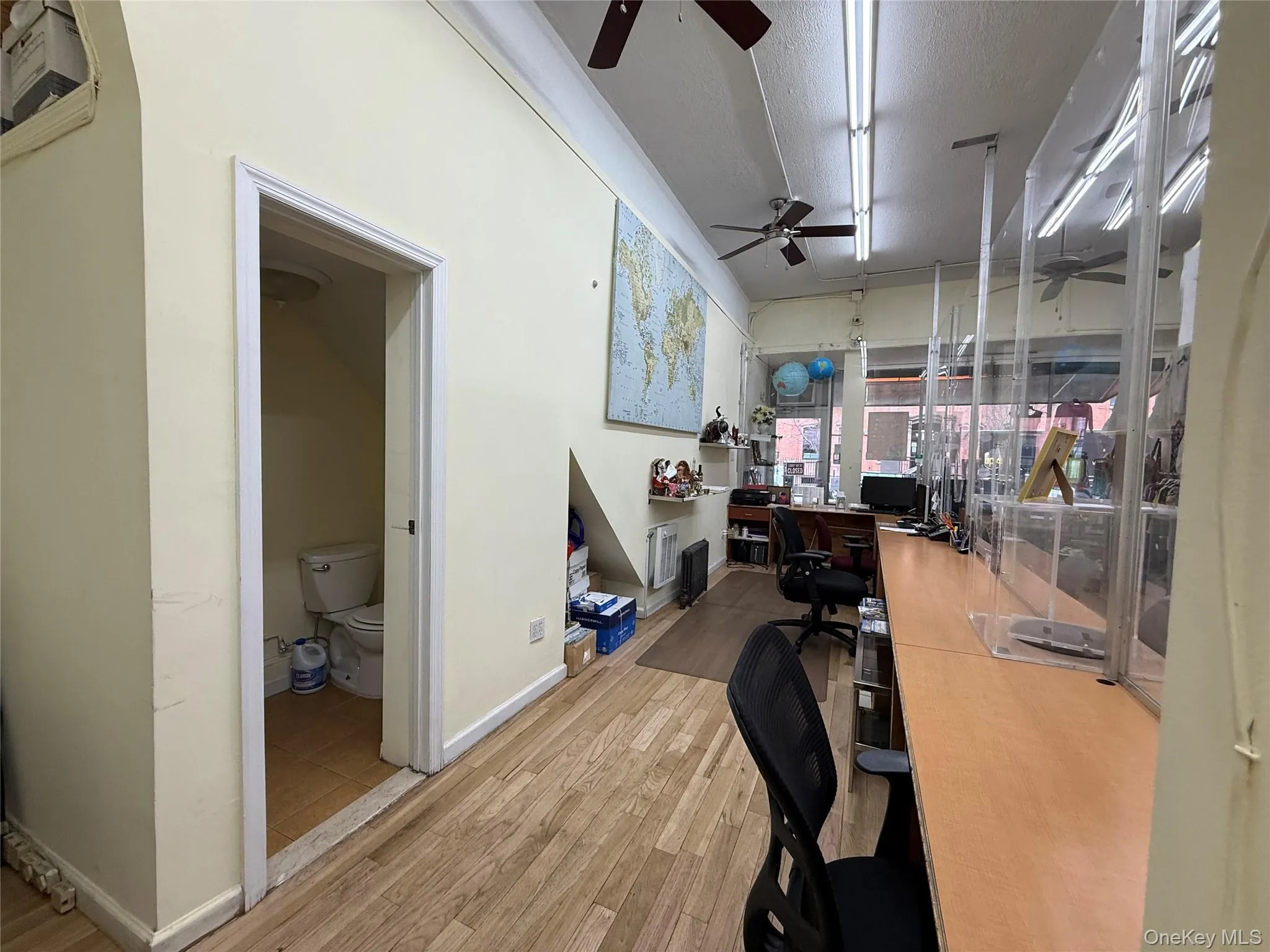Office space with light wood finished floors, a ceiling fan, and a textured ceiling Office space with light wood finished floors, a ceiling fan, and a textured ceiling