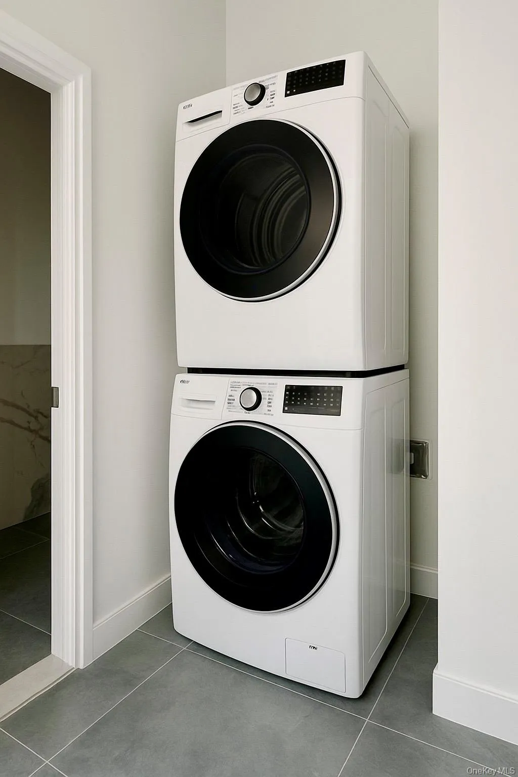 Laundry room with stacked washer and clothes dryer and tile patterned floors Laundry room with stacked washer and clothes dryer and tile patterned floors
