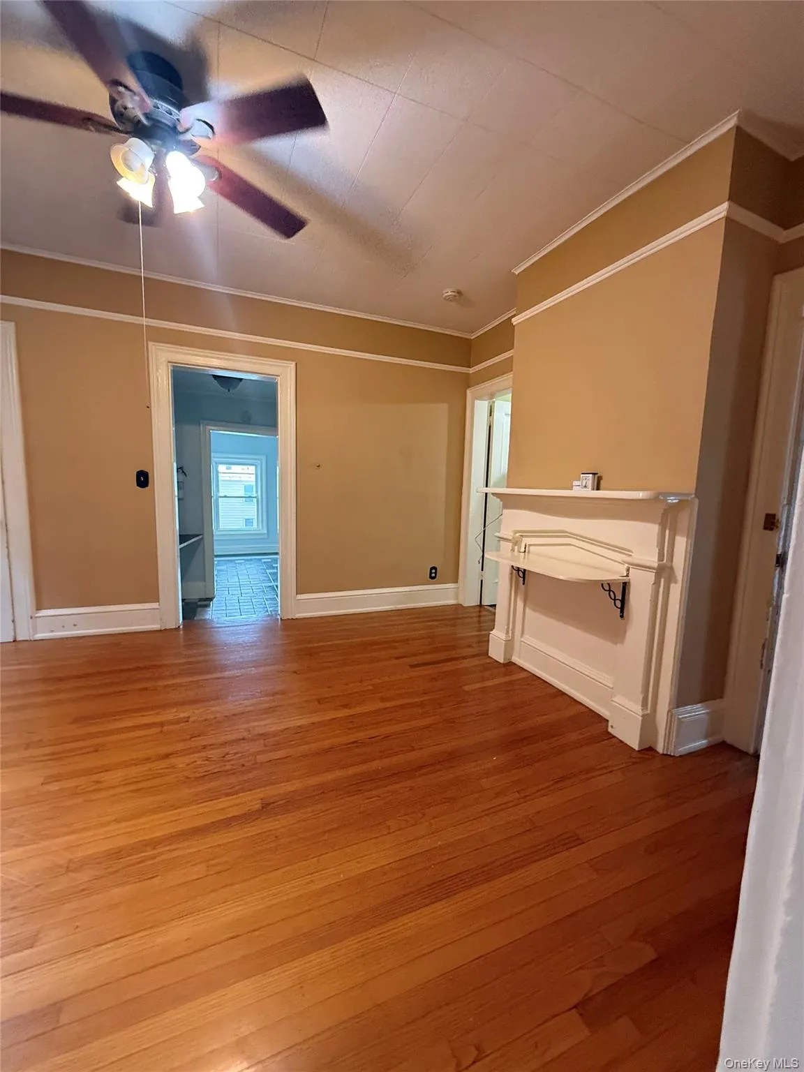 Unfurnished living room with light wood-style floors, ornamental molding, and a ceiling fan Unfurnished living room with light wood-style floors, ornamental molding, and a ceiling fan