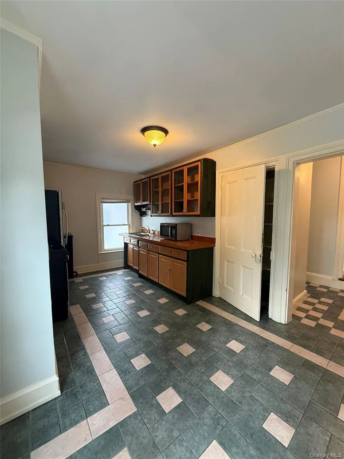 Kitchen with glass insert cabinets, stainless steel appliances, dark countertops, and brown cabinetry Kitchen with glass insert cabinets, stainless steel appliances, dark countertops, and brown cabinetry