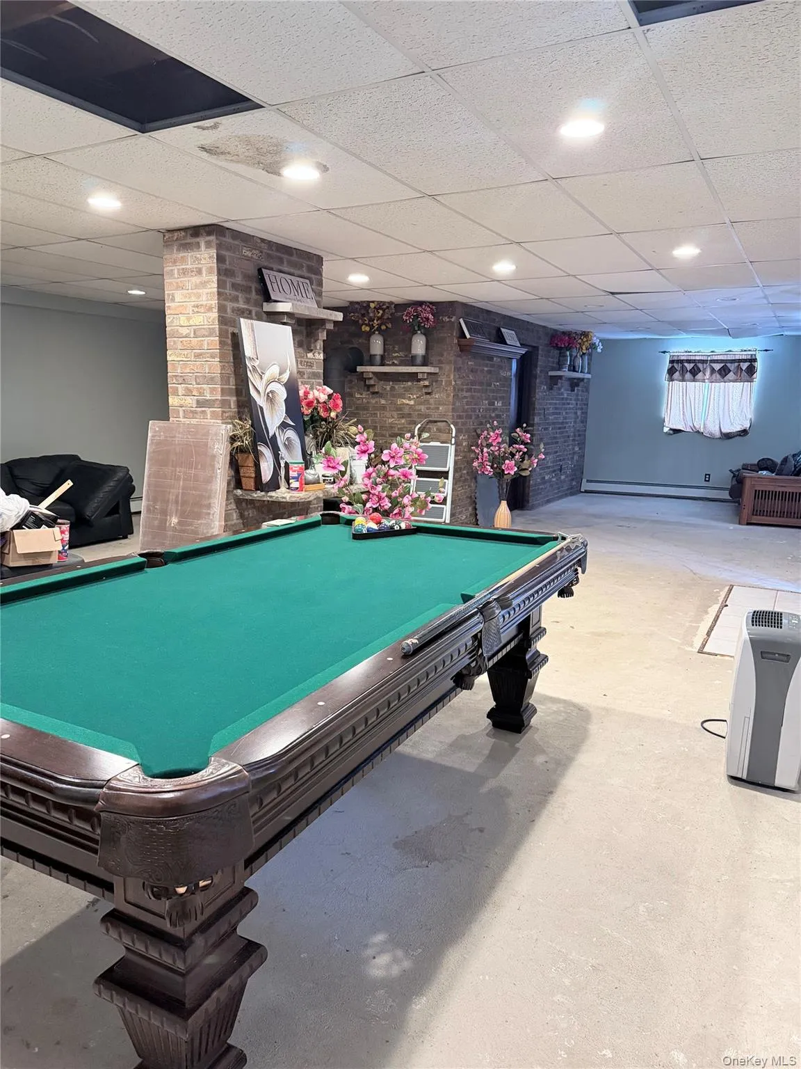 Rec room featuring unfinished concrete floors, billiards, and brick wall Rec room featuring unfinished concrete floors, billiards, and brick wall