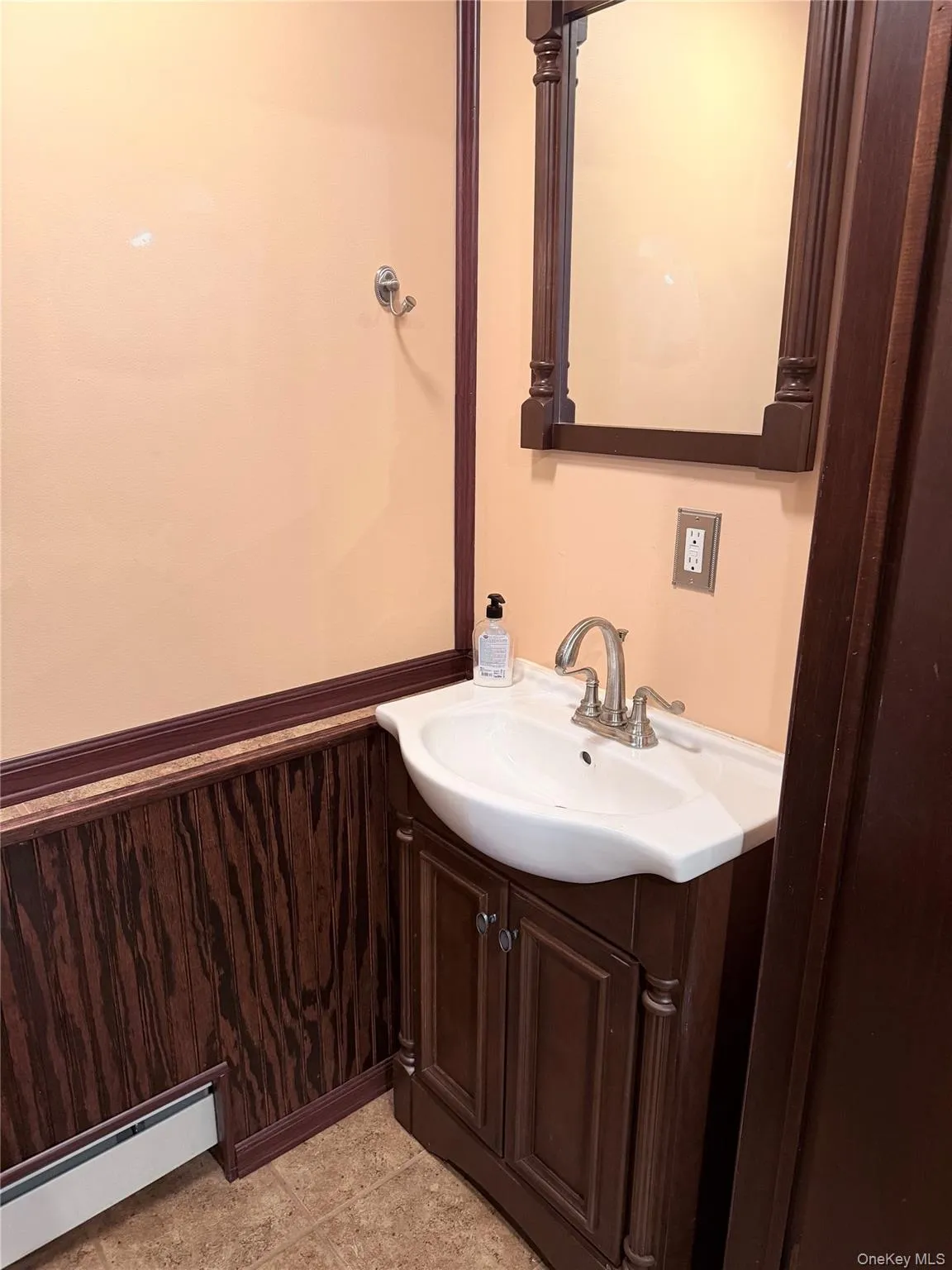 Bathroom with a baseboard heating unit, vanity, wooden walls, and a wainscoted wall Bathroom with a baseboard heating unit, vanity, wooden walls, and a wainscoted wall