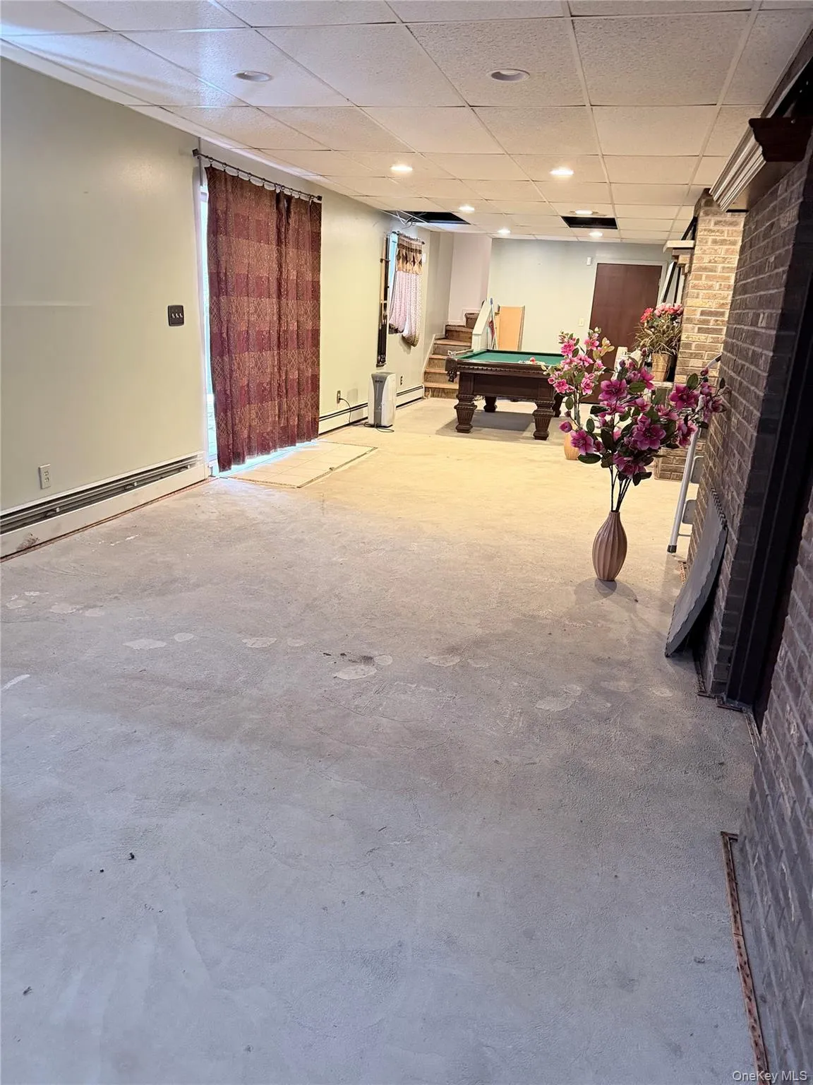 Game room featuring a baseboard radiator, billiards table, a drop ceiling, and concrete floors Game room featuring a baseboard radiator, billiards table, a drop ceiling, and concrete floors