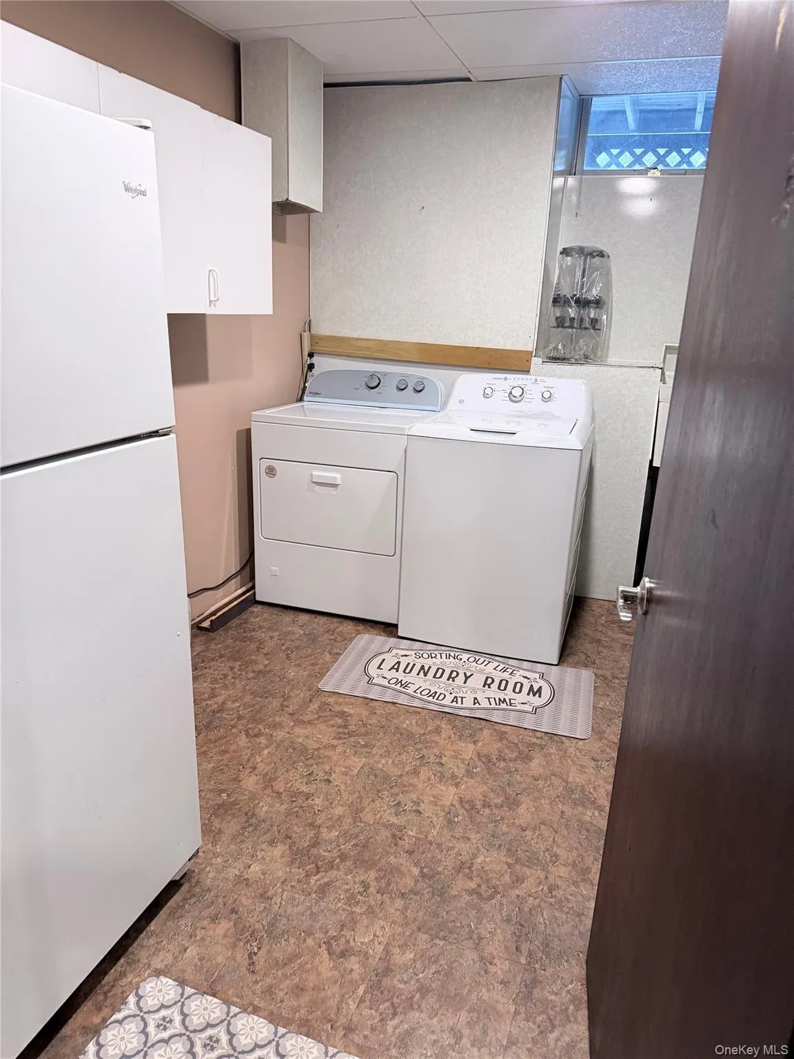 Washroom with separate washer and dryer, dark flooring, and a paneled ceiling Washroom with separate washer and dryer, dark flooring, and a paneled ceiling