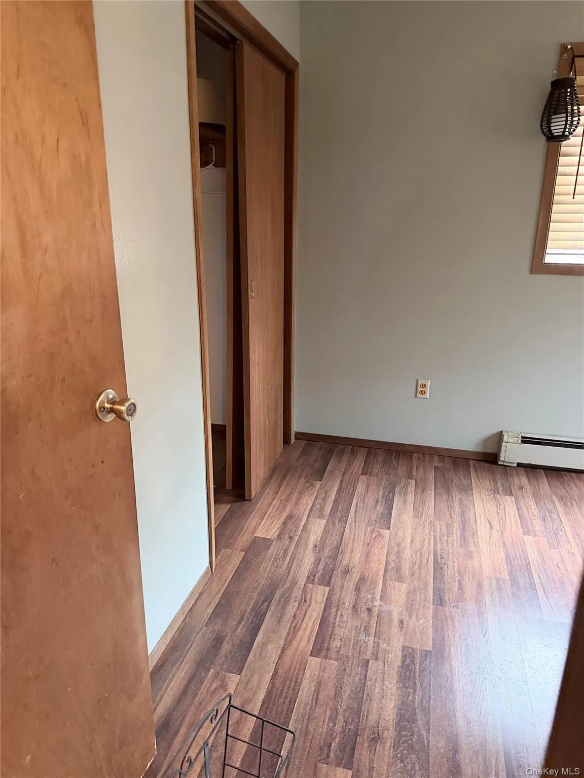 Unfurnished bedroom with wood finished floors and a baseboard radiator Unfurnished bedroom with wood finished floors and a baseboard radiator