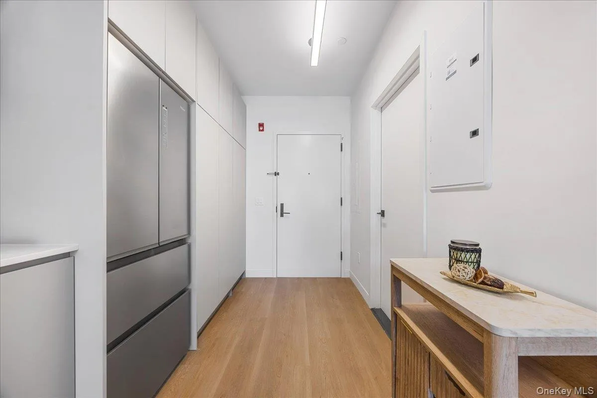 Hall with light wood-style floors and electric panel Hall with light wood-style floors and electric panel