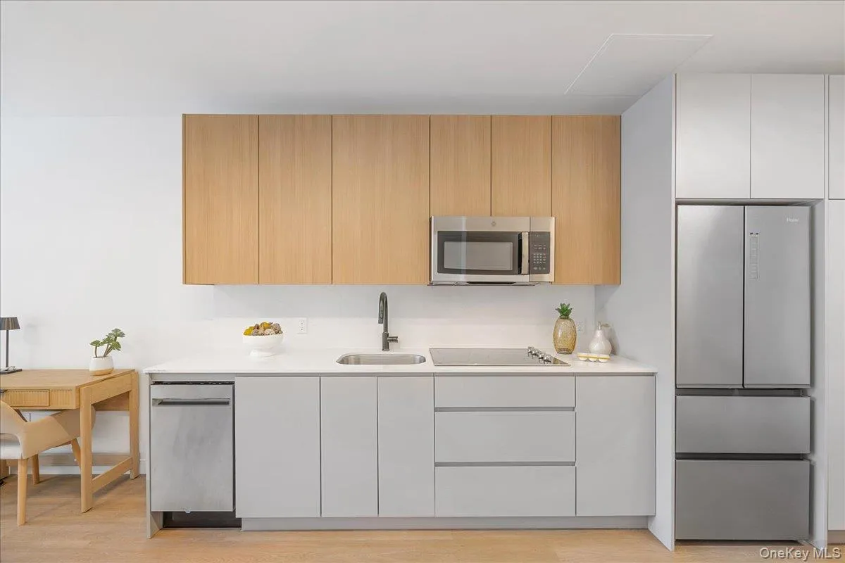 Kitchen with modern cabinets, stainless steel appliances, light stone counters, light wood-style floors, and light brown cabinets Kitchen with modern cabinets, stainless steel appliances, light stone counters, light wood-style floors, and light brown cabinets