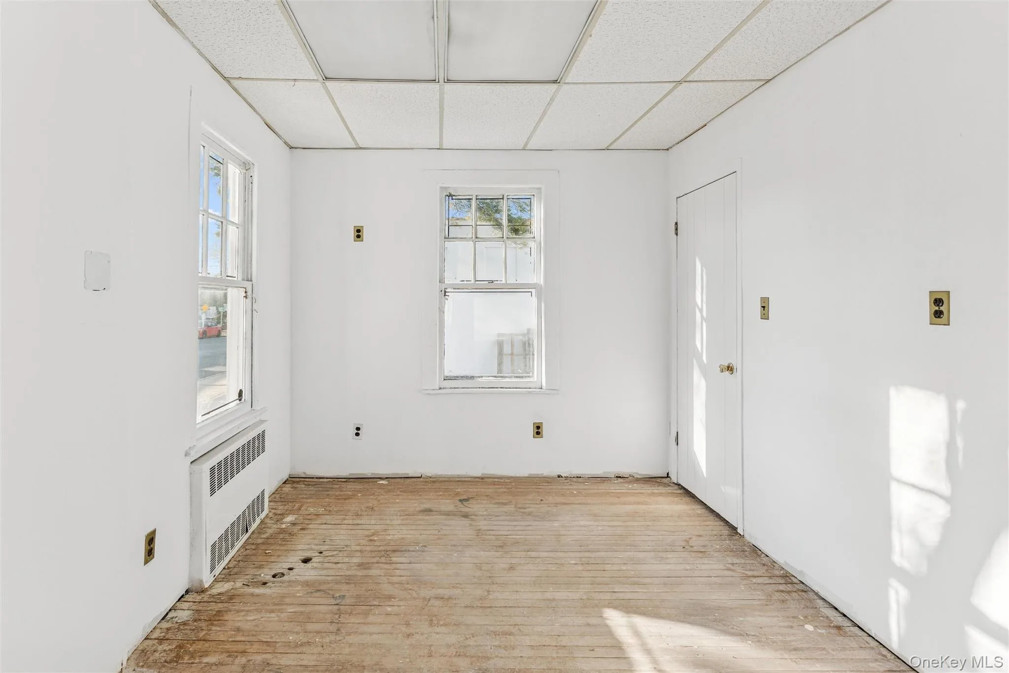 Foyer entrance with radiator, light wood-style flooring, and a paneled ceiling Foyer entrance with radiator, light wood-style flooring, and a paneled ceiling