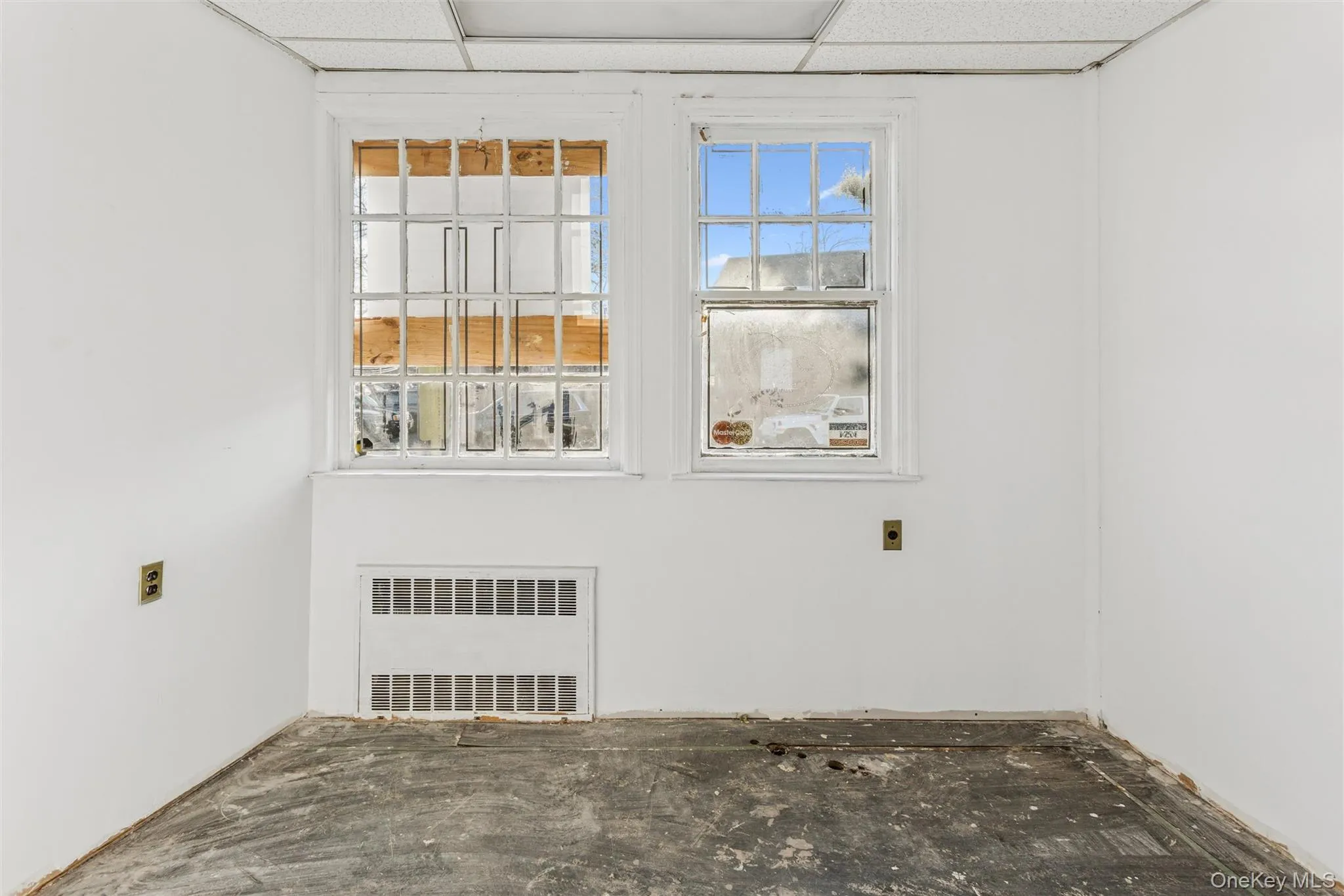 Empty room featuring radiator heating unit and a paneled ceiling Empty room featuring radiator heating unit and a paneled ceiling