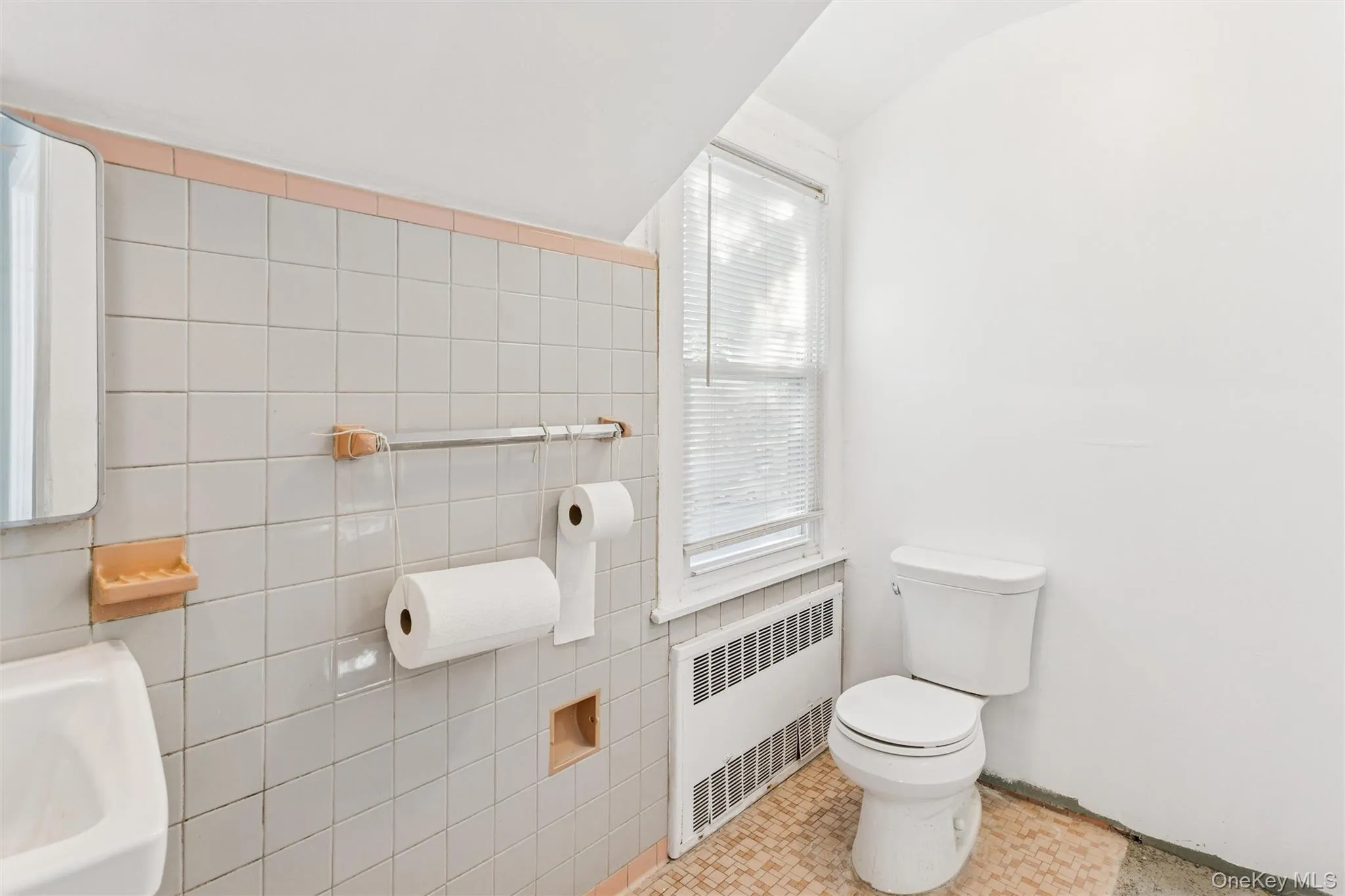 Bathroom featuring radiator, tile walls, vaulted ceiling, and light tile patterned flooring Bathroom featuring radiator, tile walls, vaulted ceiling, and light tile patterned flooring