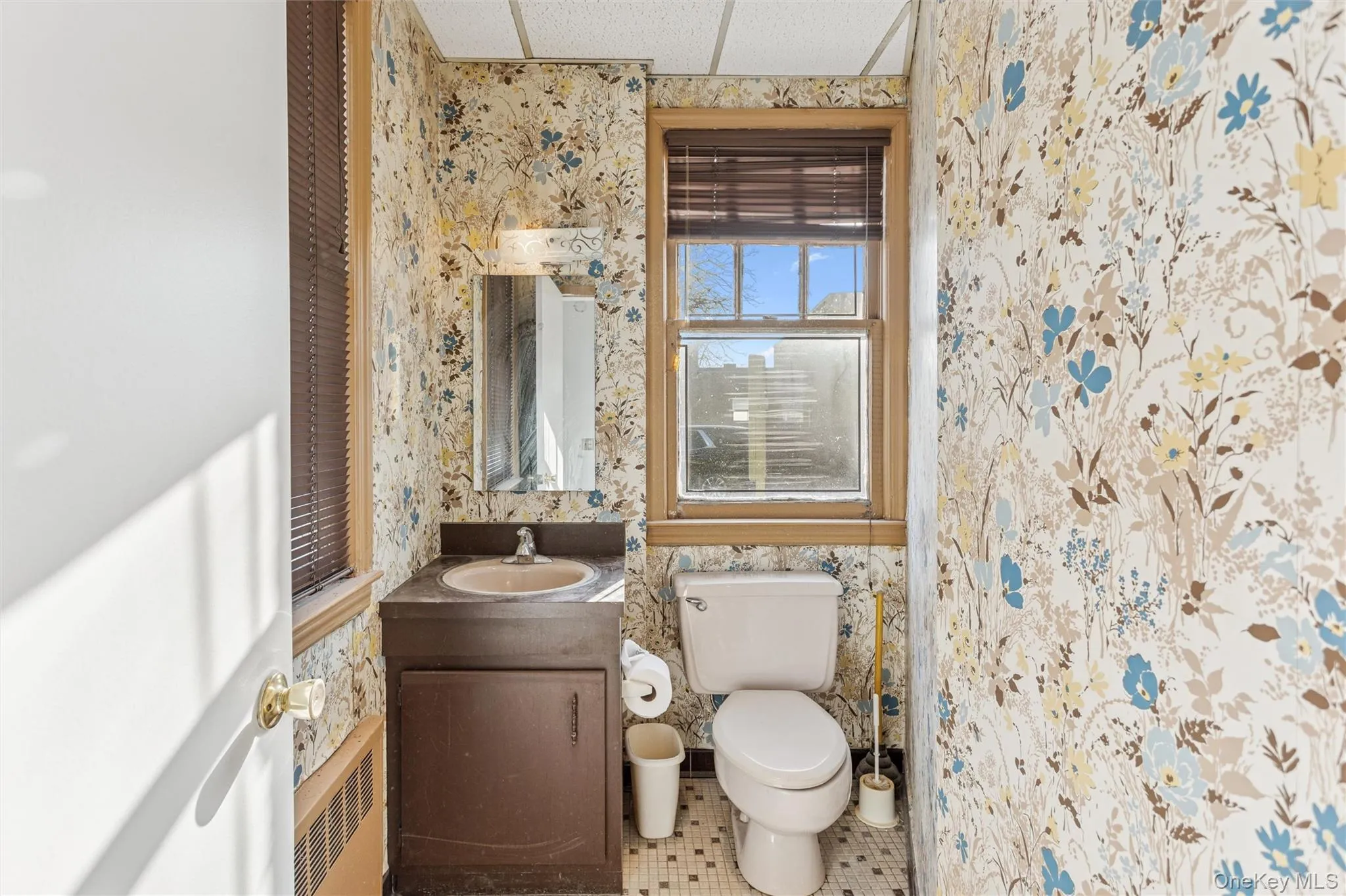 Bathroom with vanity, radiator, tile patterned flooring, wallpapered walls, and a shower with curtain Bathroom with vanity, radiator, tile patterned flooring, wallpapered walls, and a shower with curtain