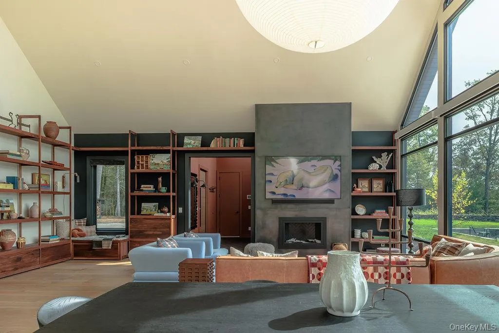 Living area with high vaulted ceiling, a large fireplace, and wood finished floors Living area with high vaulted ceiling, a large fireplace, and wood finished floors