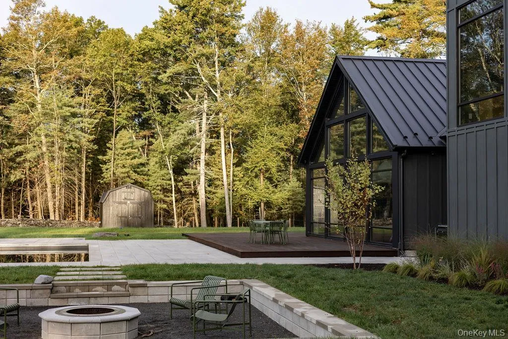 View of green lawn featuring a fire pit, a deck, a sunroom, a storage unit, and a patio area View of green lawn featuring a fire pit, a deck, a sunroom, a storage unit, and a patio area