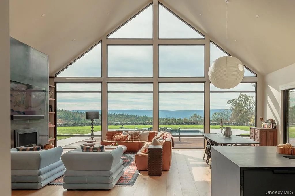 Living room with high vaulted ceiling, a wall of windows, and light wood-type flooring Living room with high vaulted ceiling, a wall of windows, and light wood-type flooring